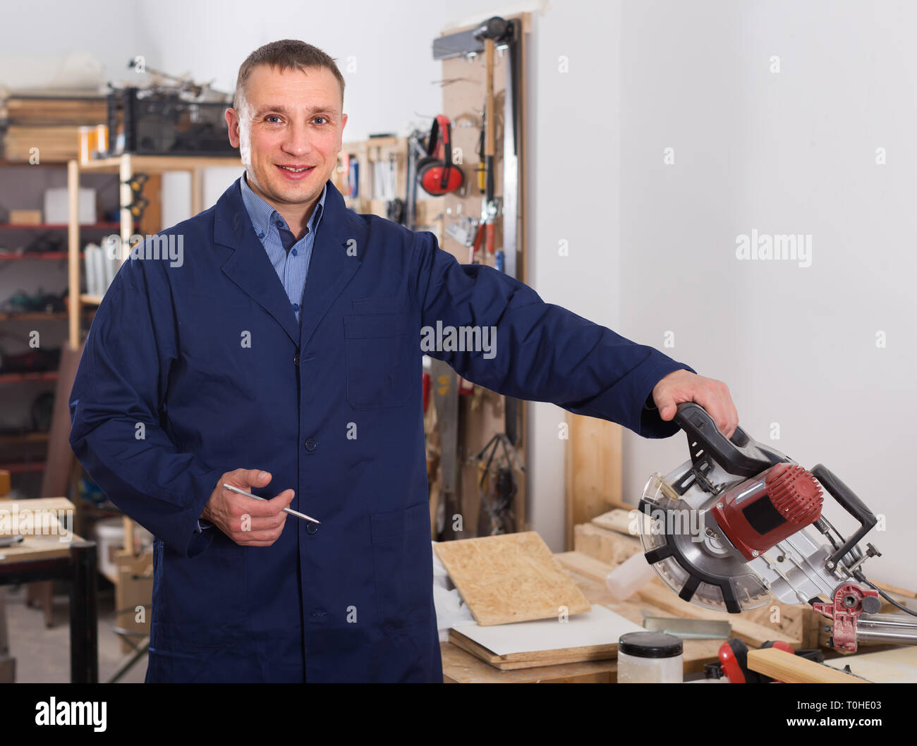 happy spanish carpenter with fret saw cutting wood plank at