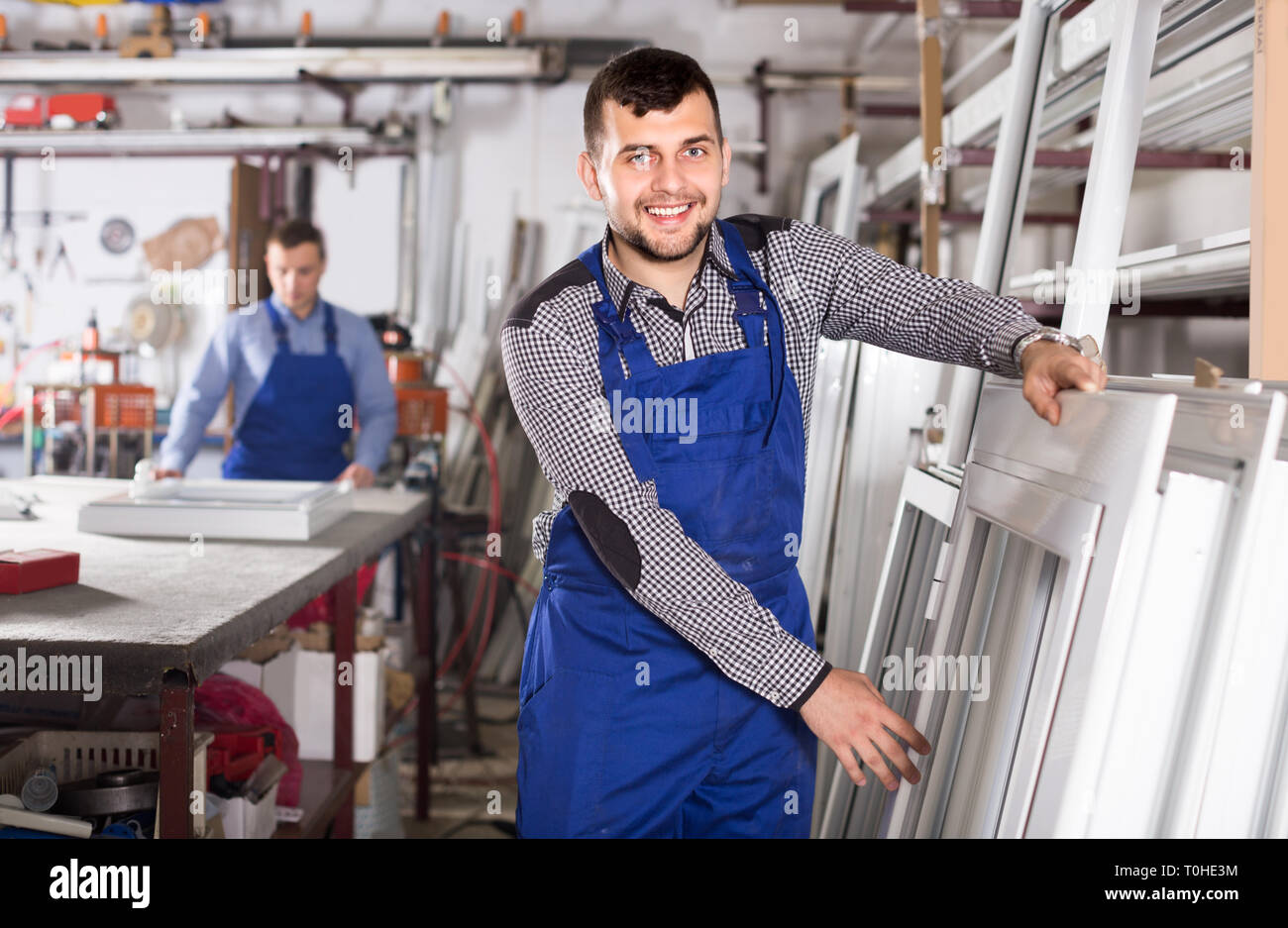 Young laborer is inspecting the window frame in workshop. Stock Photo