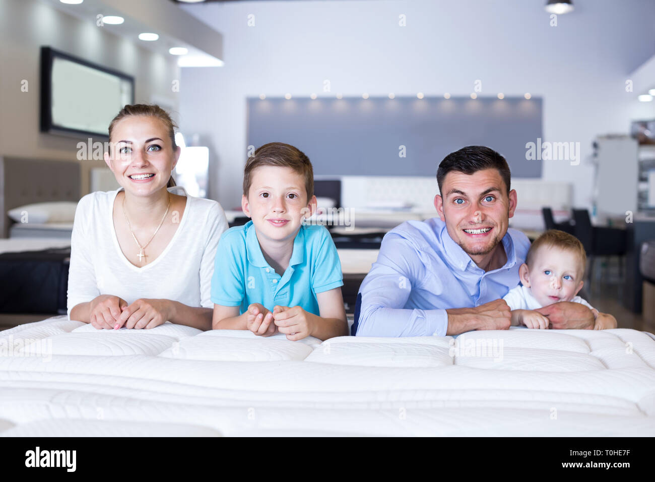 happy russian parents with two young sons testing mattress in store ...