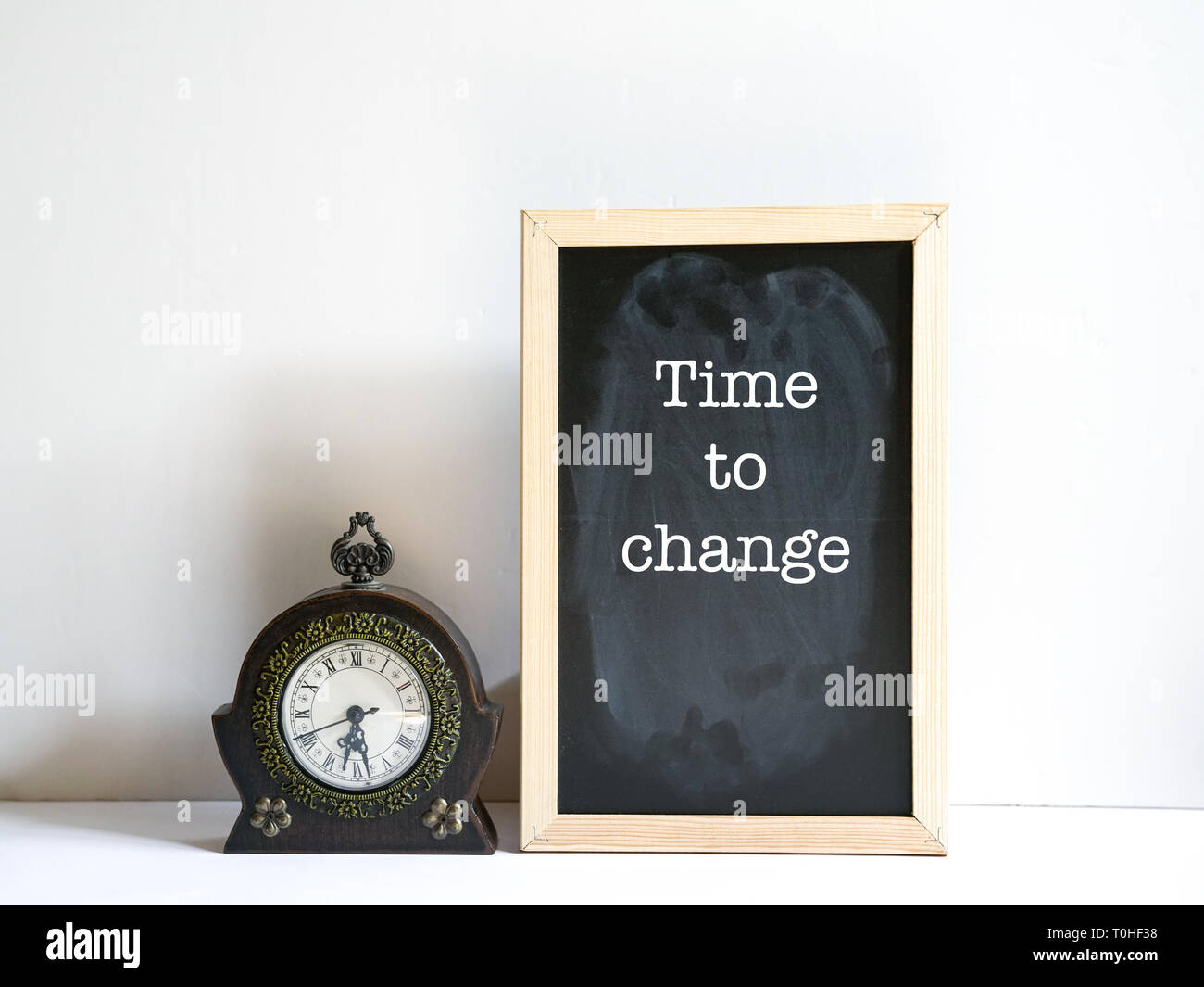 Time to change concept - message on board with an antique clock by the side Stock Photo