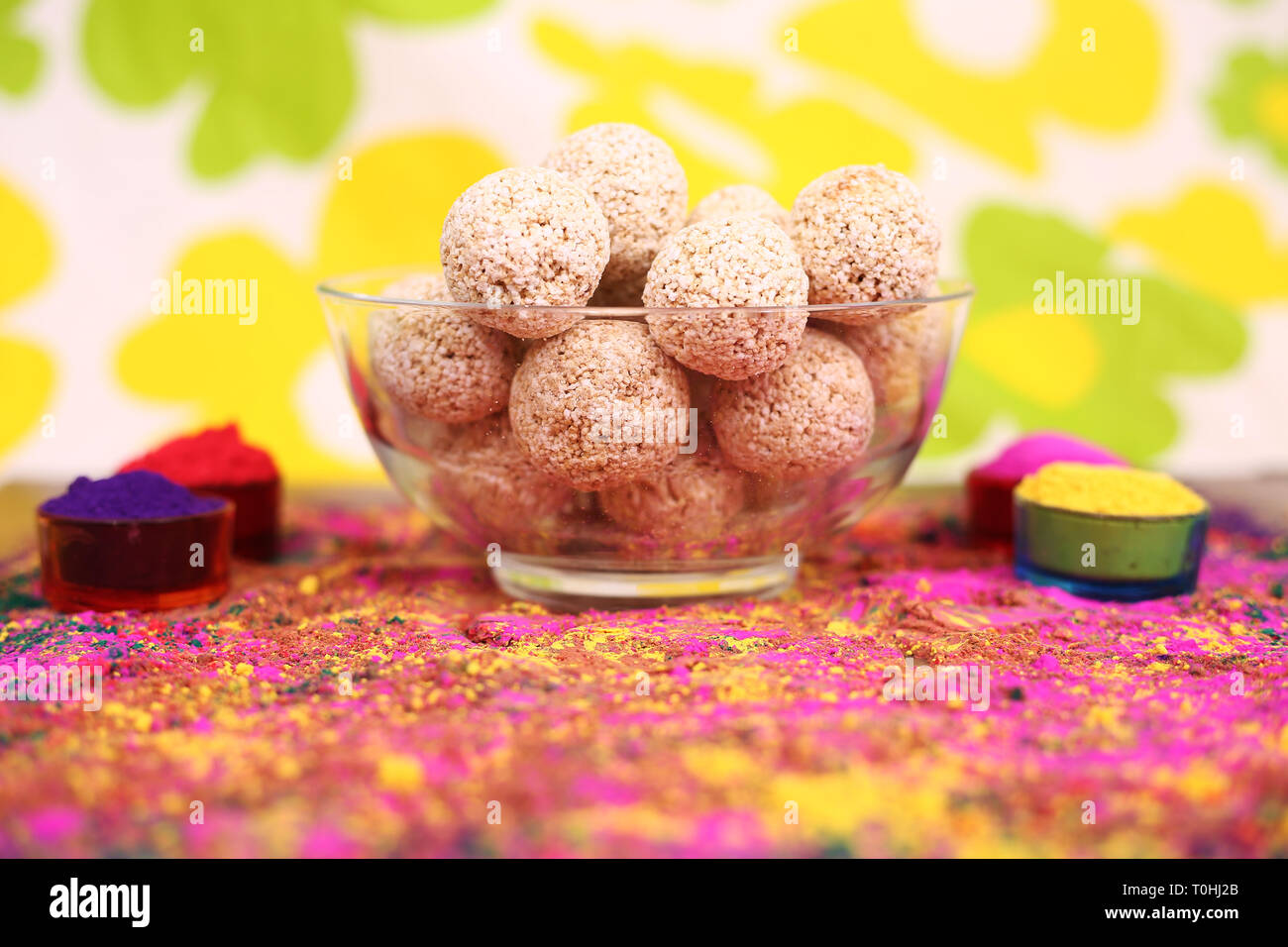 Portrait of organic holi color with cholai ke ladoo in the bowl. Isolated on the colorful background. Stock Photo