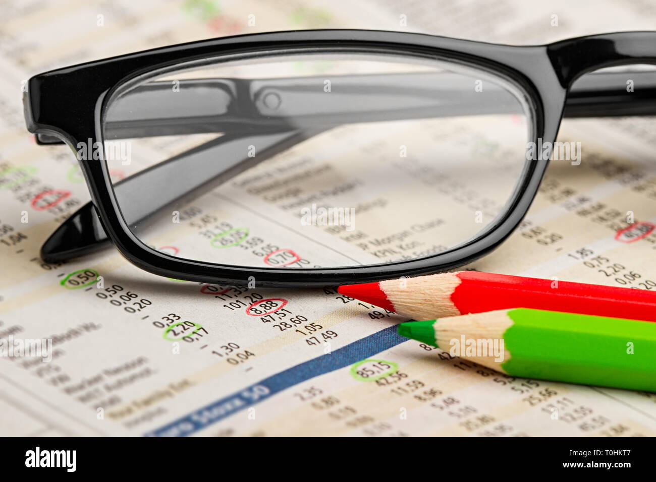 glasses red green pen pencil on newspaper with stock market exchange data chart finance business concept cash background Stock Photo