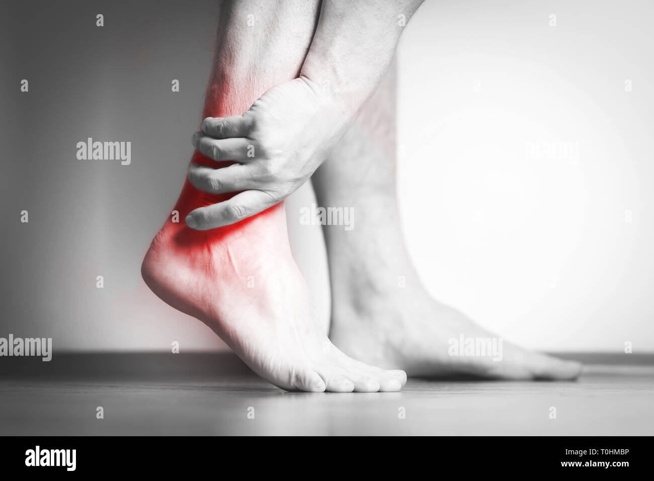 Causian man holds hands to his painful feet, pain in foot. Black and