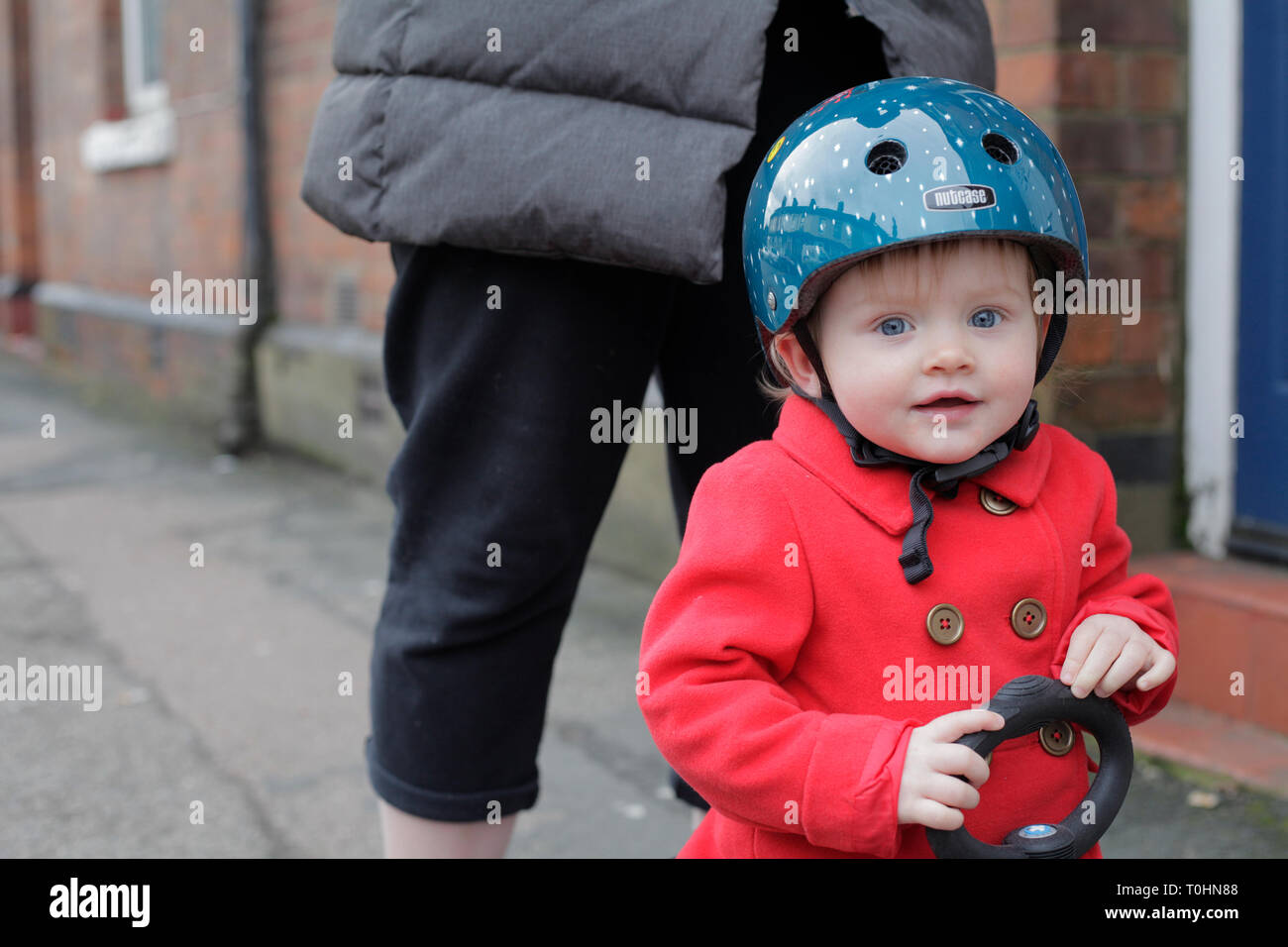 Toddler in a bicycle helmet learning to use a scooter Stock Photo