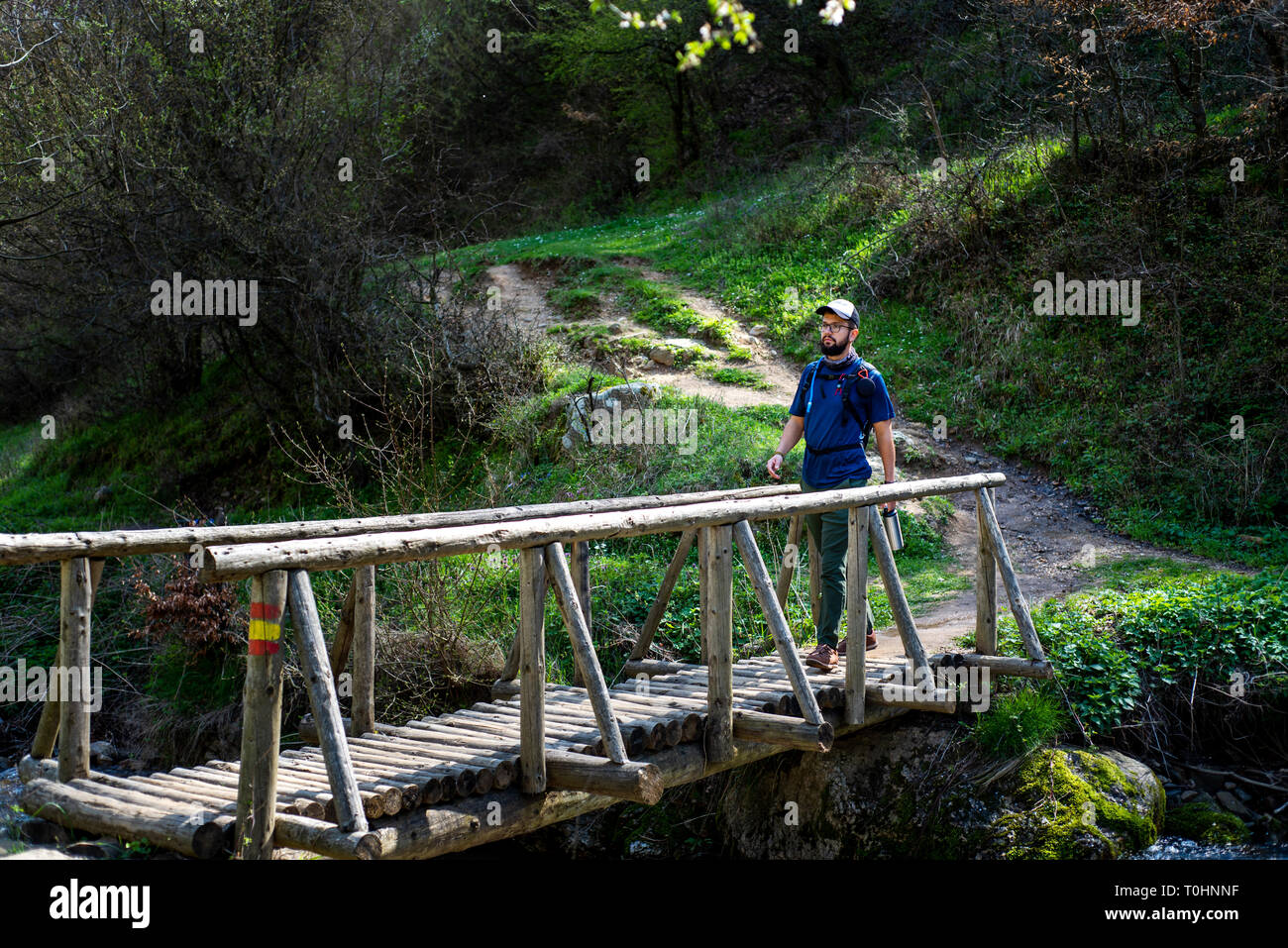 Hiker crossing the wooden bridge over small river Stock Photo