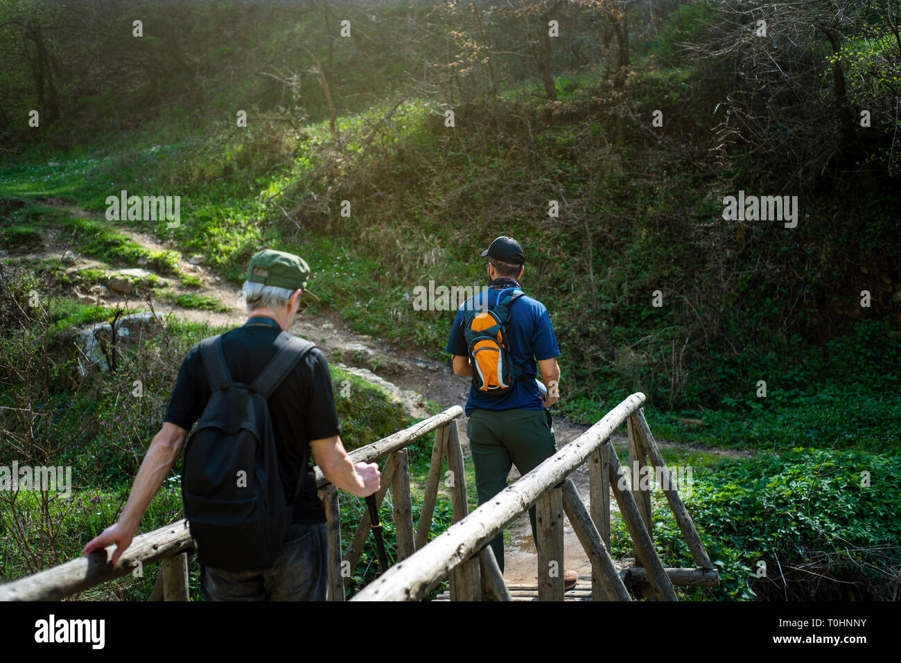Hikers crossing the wooden bridge over small river Stock Photo