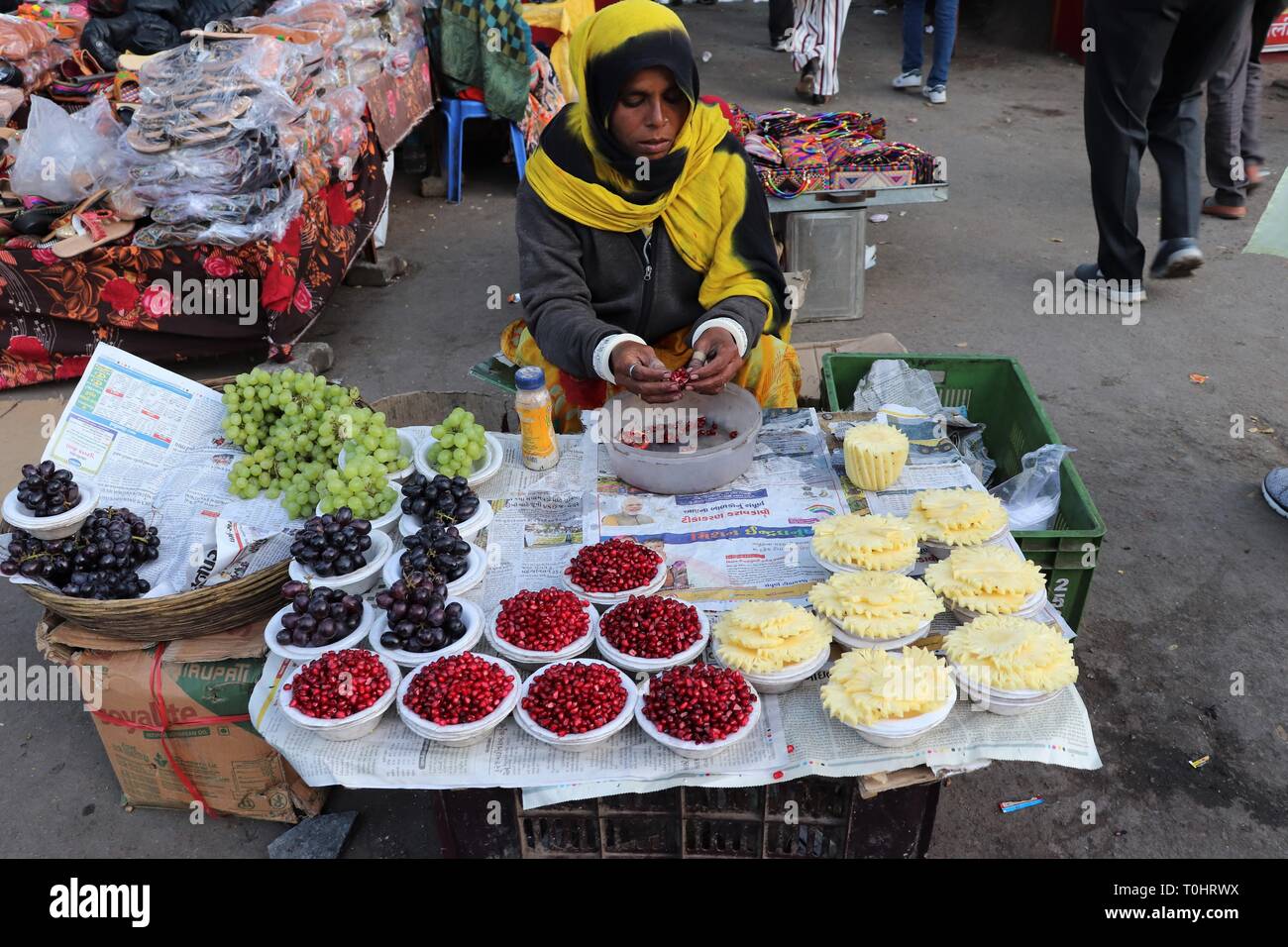 A woman peeling pomegranate fruit on the streets of Mount Abu-Rajasthan,India. Stock Photo