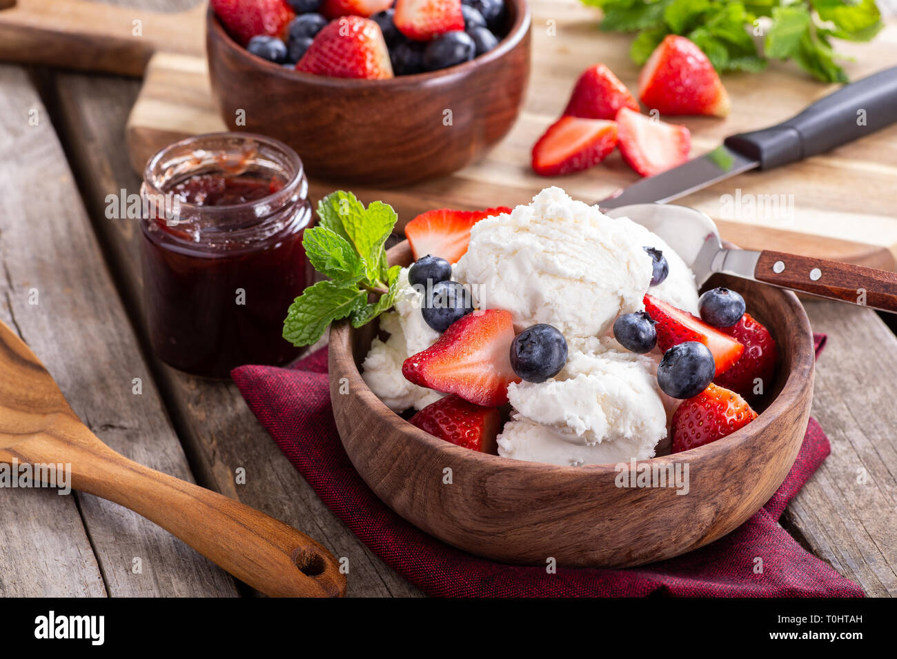 Wooden bowl of vanilla ice cream with blueberries and strawberries on a ...