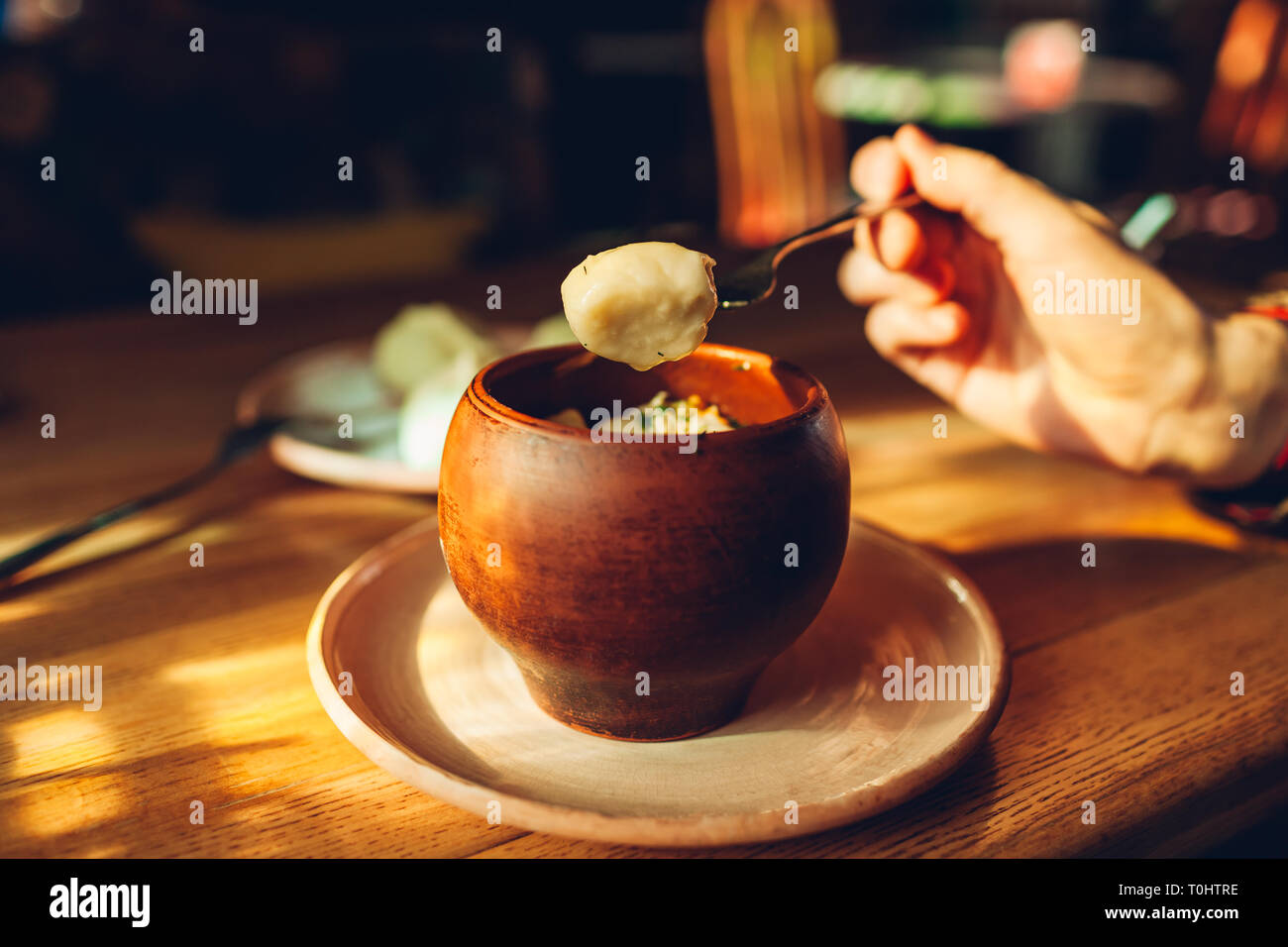 Delicious dumplings with chicken and dill in clay pot and drinks served in cafe. Ukrainian