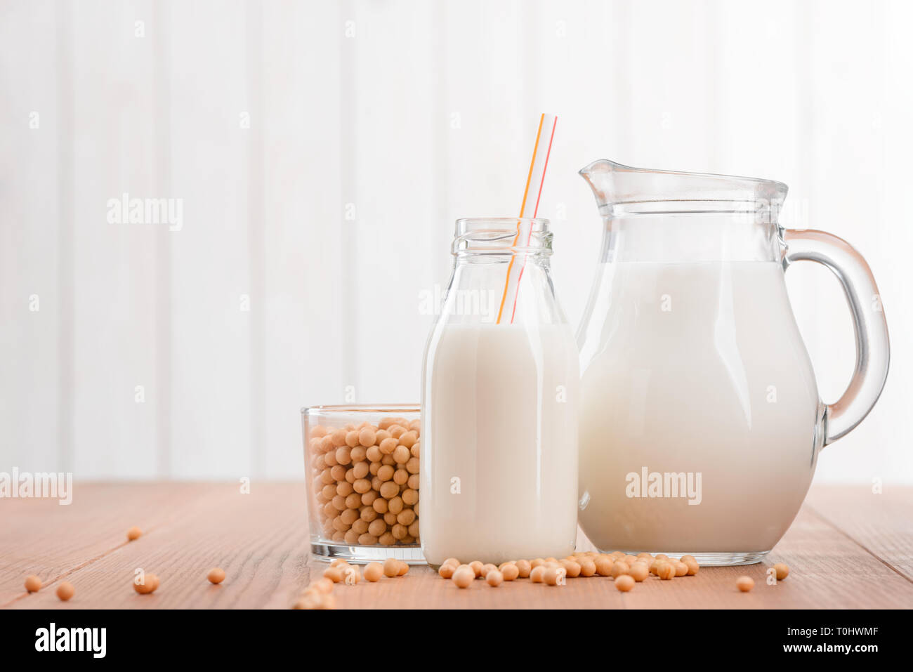 Jug and bottle of soy milk and cup of beans. Homemade non-dairy products, alternative to cow's milk. Stock Photo