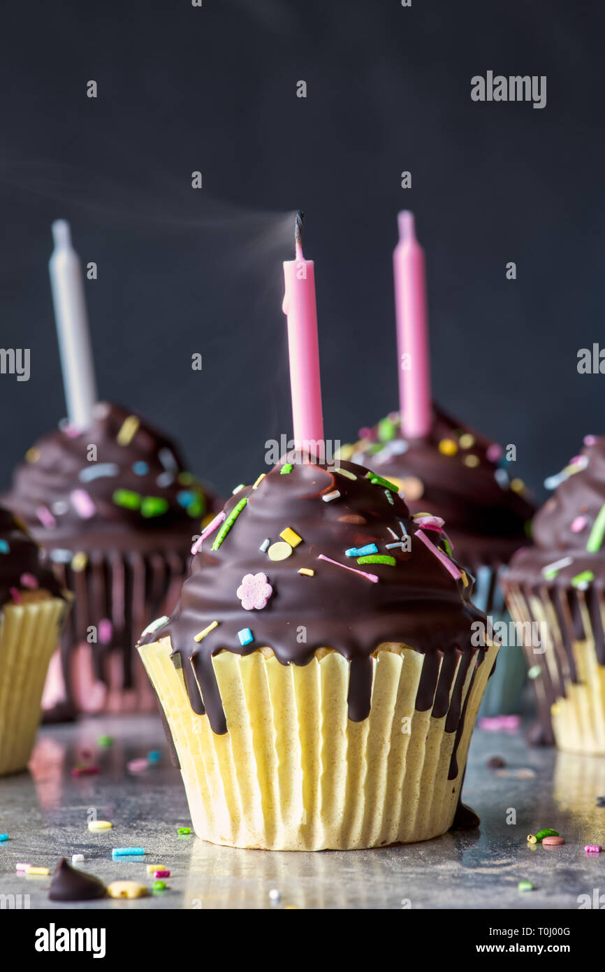 Birthday cupcakes with candles. Vanilla cupcakes with a meringue frosting and dark chocolate shell Stock Photo