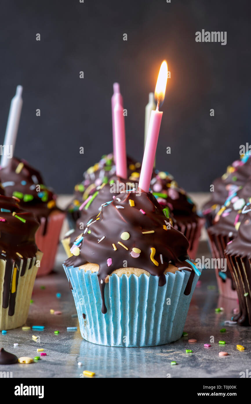 Birthday cupcakes with candles. Vanilla cupcakes with a meringue frosting and dark chocolate shell Stock Photo