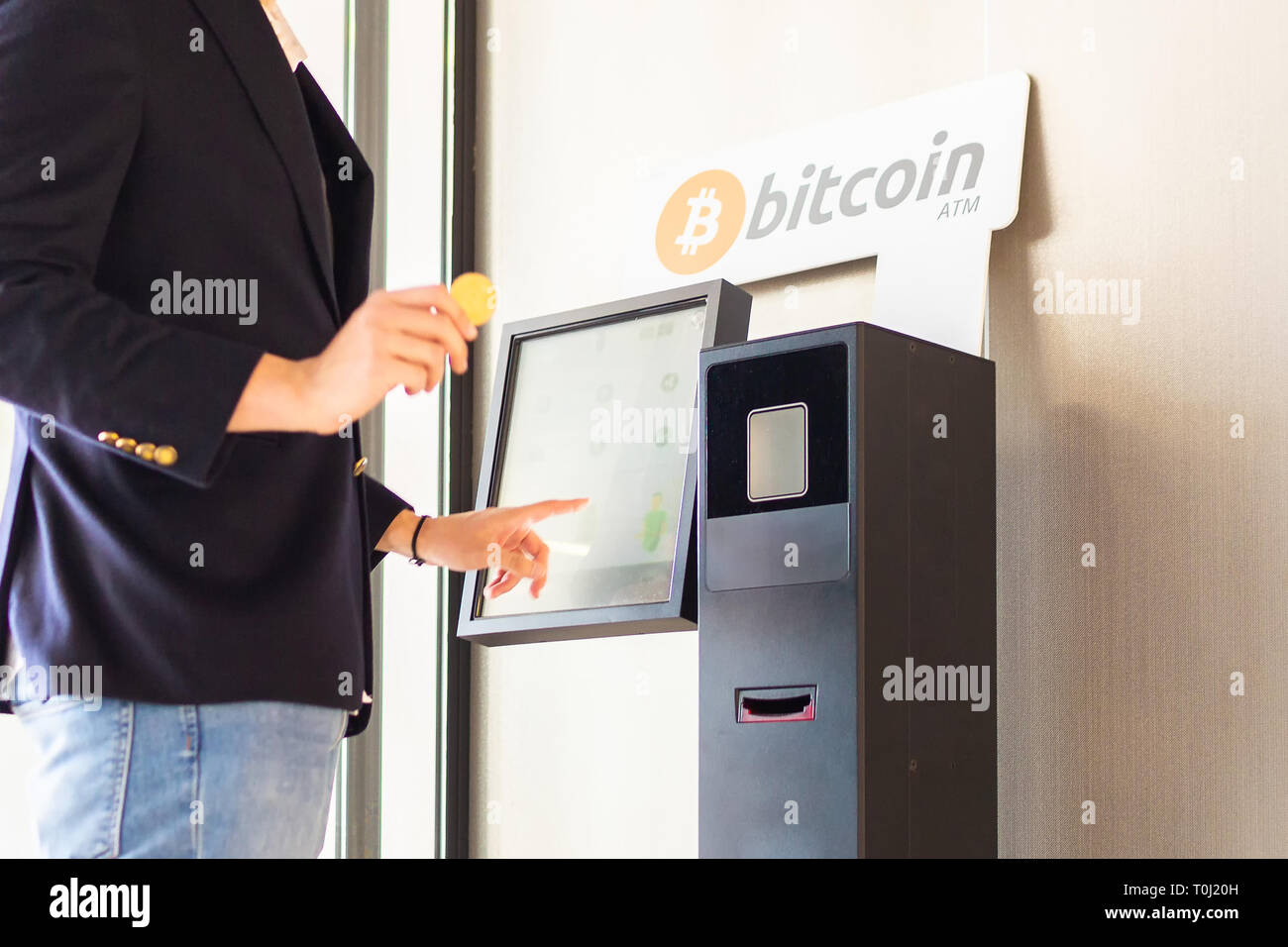 Bitcoin ATM machine being used by businessman for buying cryptocurrency and other altcoins Stock Photo