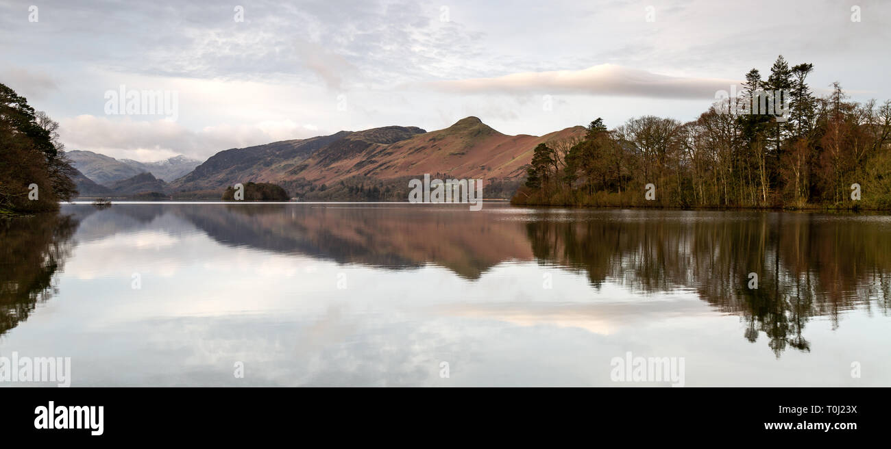 Mountains and trees reflected in the still Derwent Water as sunrise Stock Photo