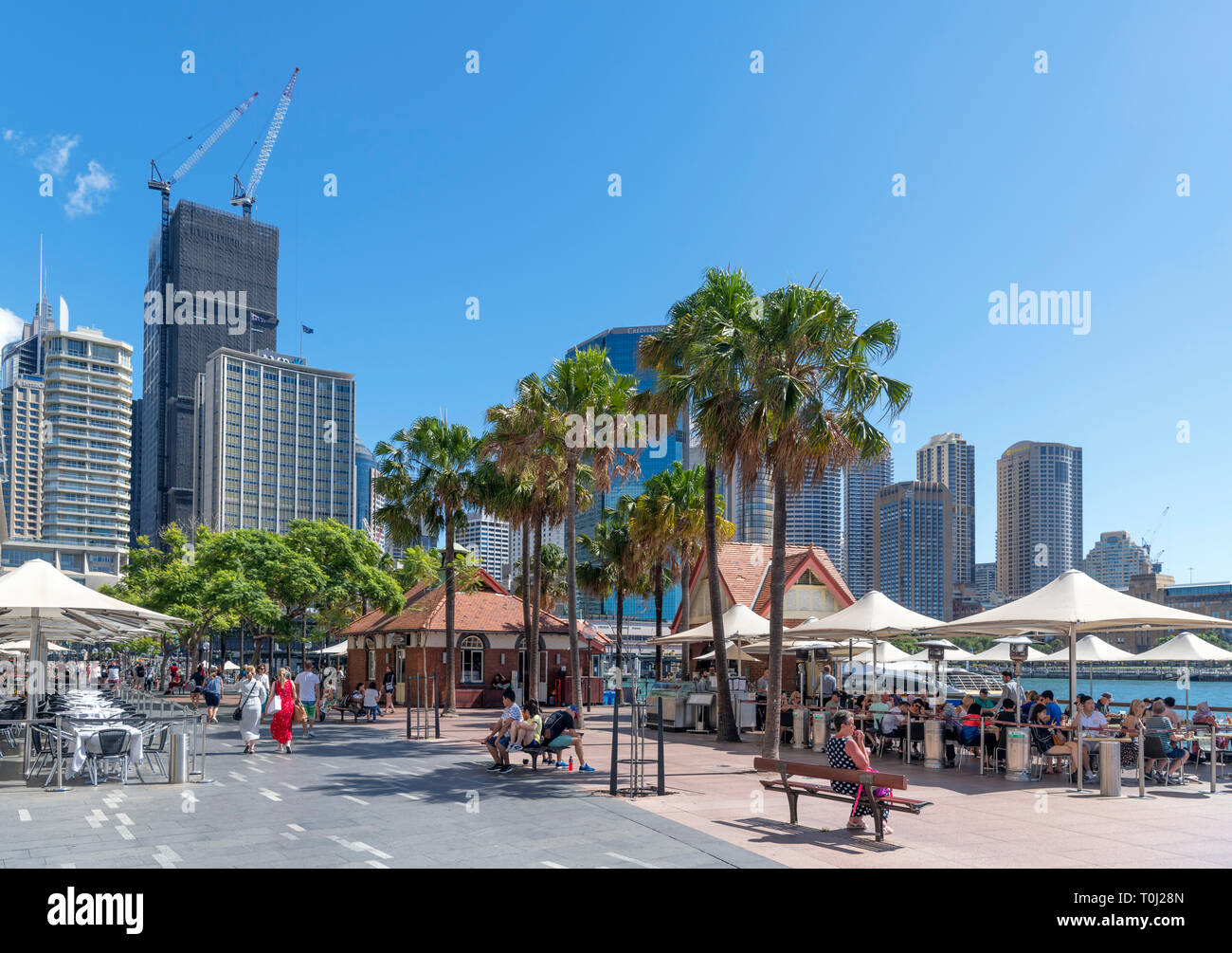 Sidewalk cafes on Circular Quay with the skyline of Sydney Central Business District behind, Sydney, Australia Stock Photo