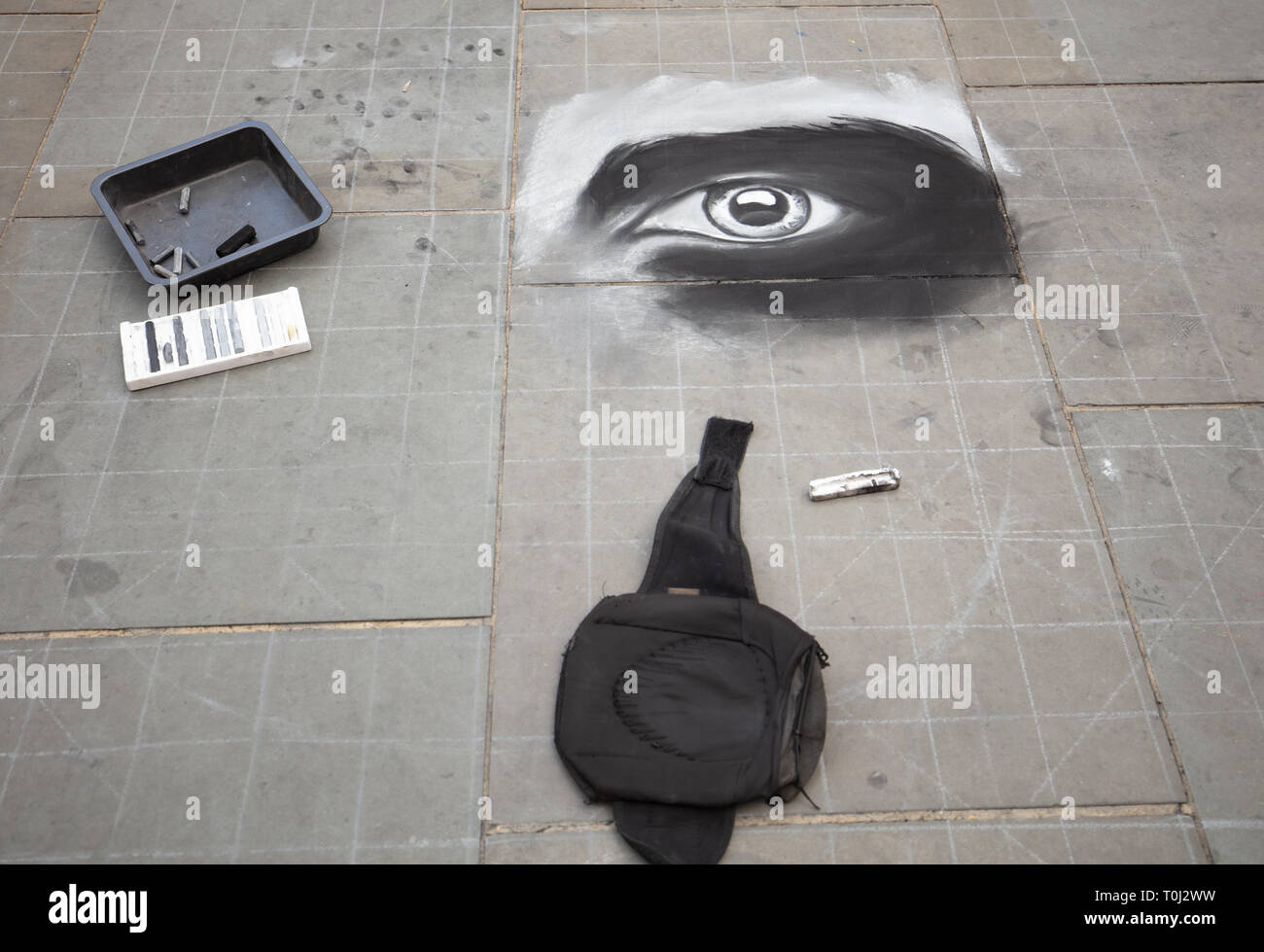 Street artist draws an eye on the paving of Piccadilly Circus London, UK to entertain and receive donations from tourists and other visitors. Stock Photo