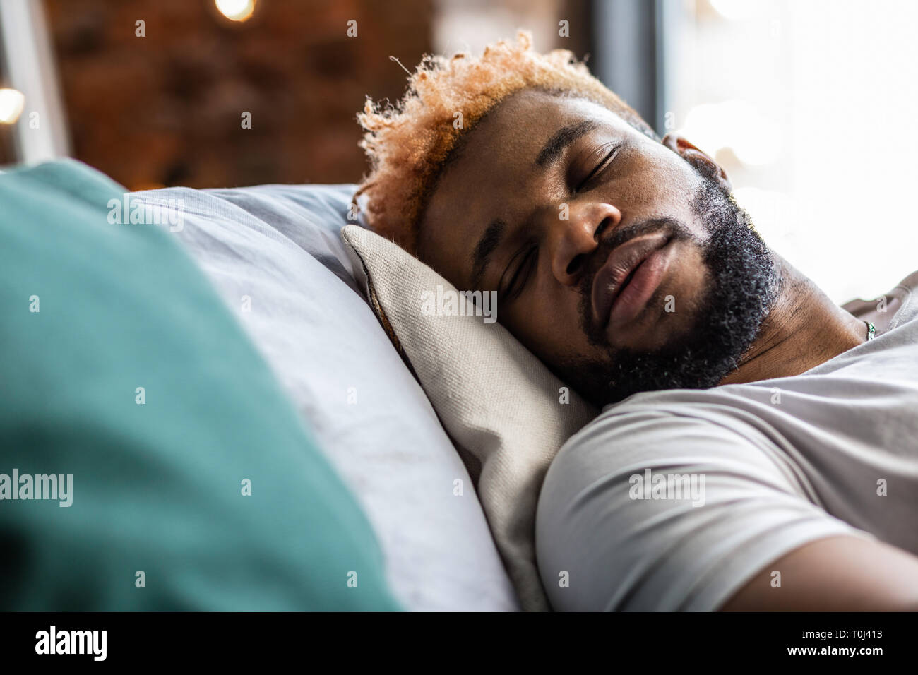 Nice pleasant young man sleeping on his bed Stock Photo