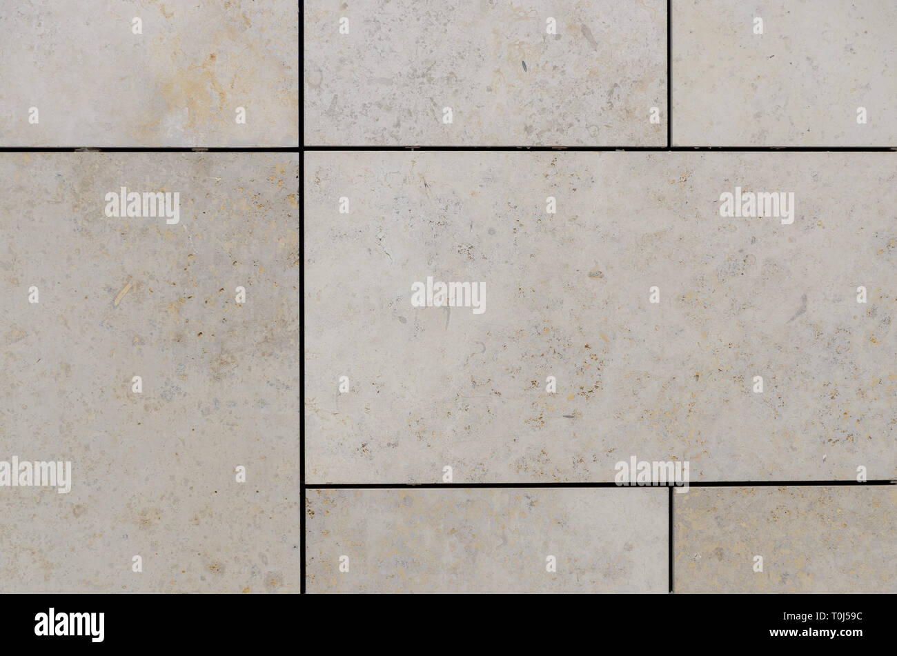 Pale beige floor tiles with dark jointing borders, viewed in close up