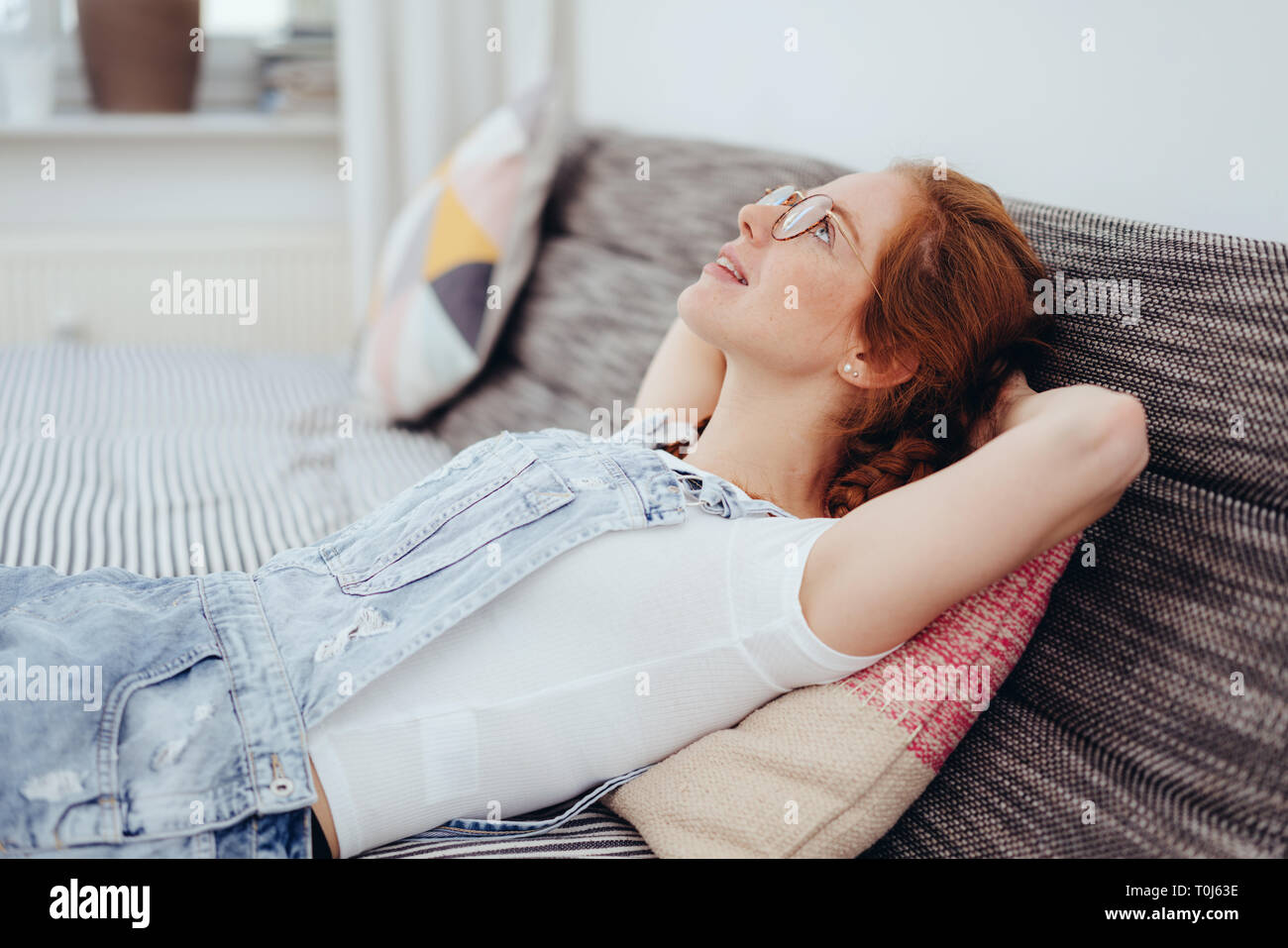 Young Woman Relaxing At Home Thinking Deeply As She Lies