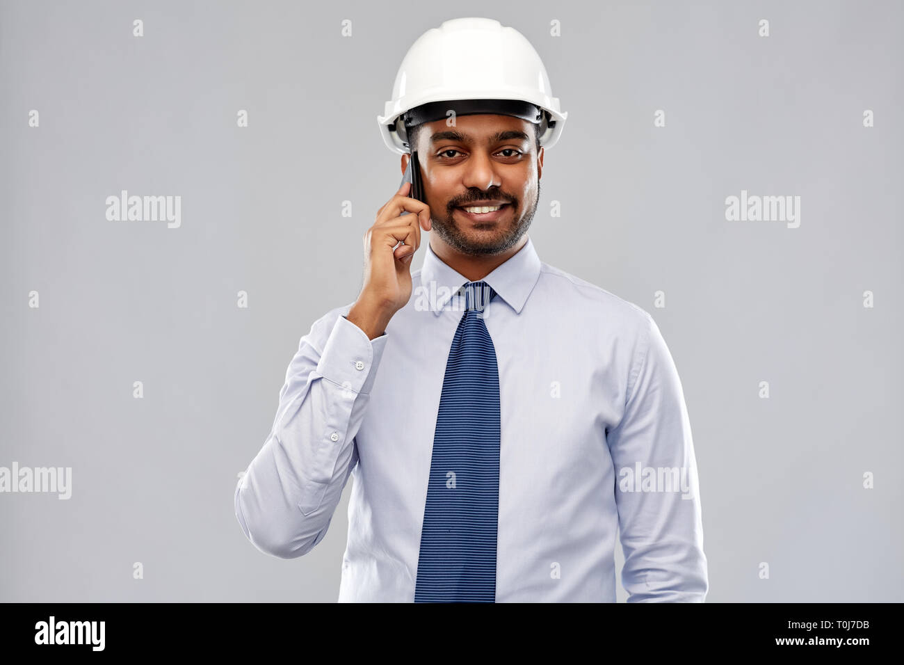 indian architect in helmet calling on smartphone Stock Photo