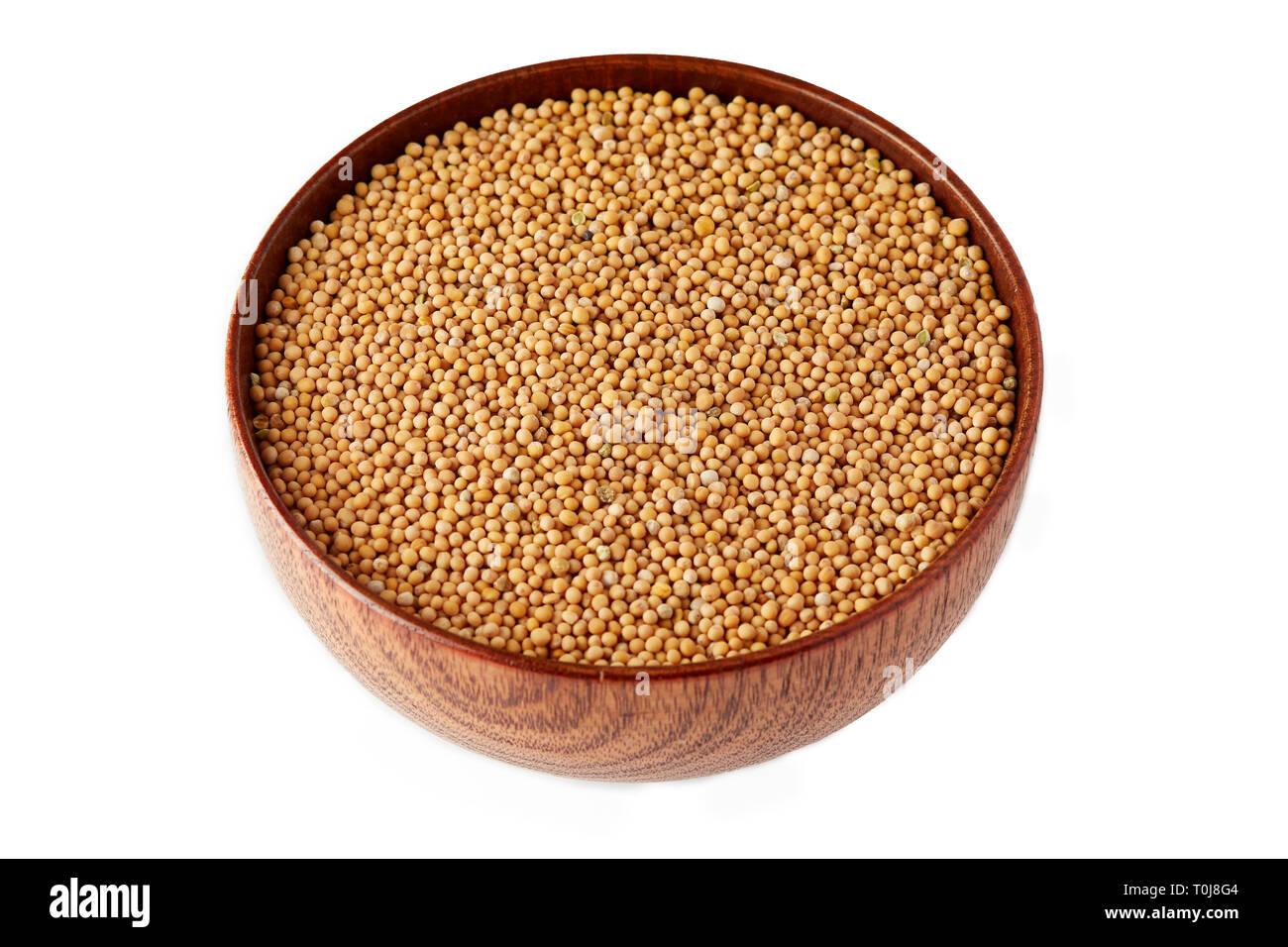 Organic yellow mustard seeds in wooden bowl isolated on white