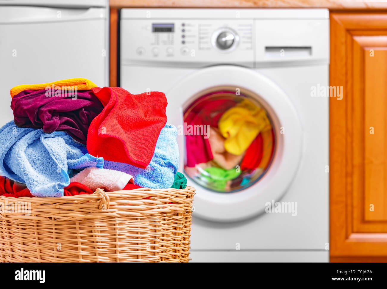 Washing machine and basket indoors. Stock Photo
