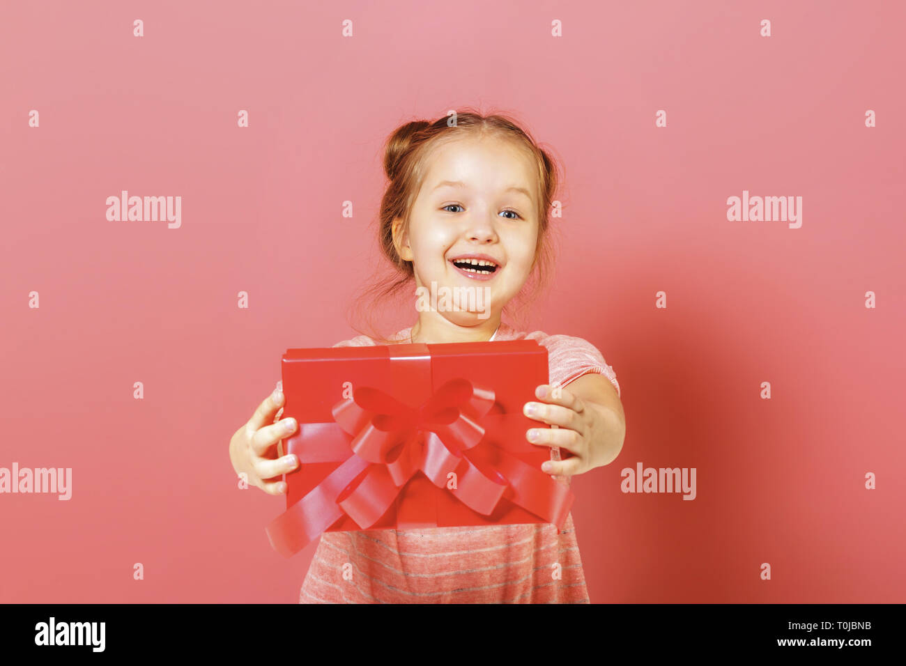 Closeup Portrait Of A Cute Little Girl With Hair Buns On Pink