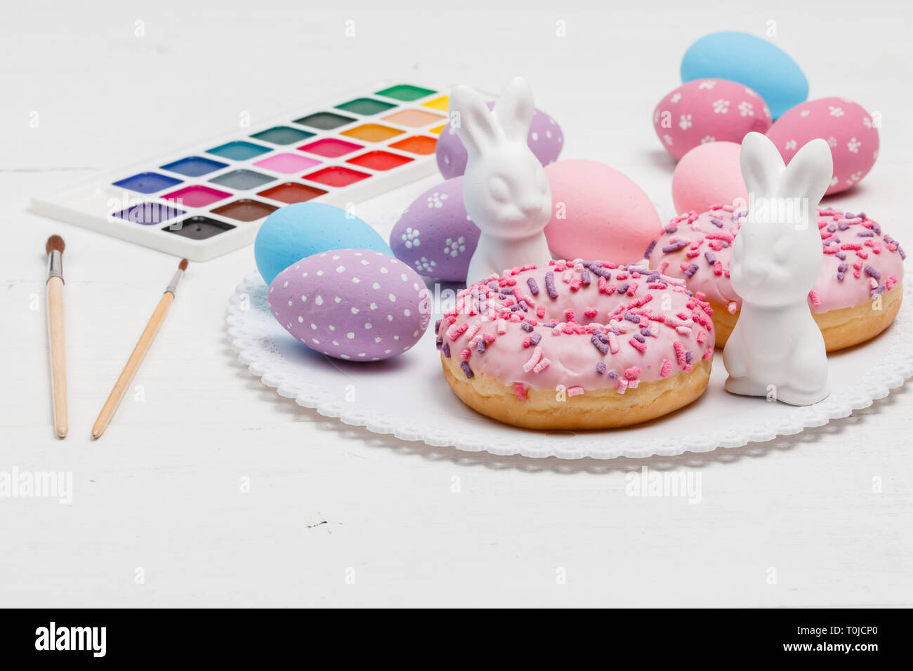 Easter bunnies and eggs on the table with donuts Stock Photo
