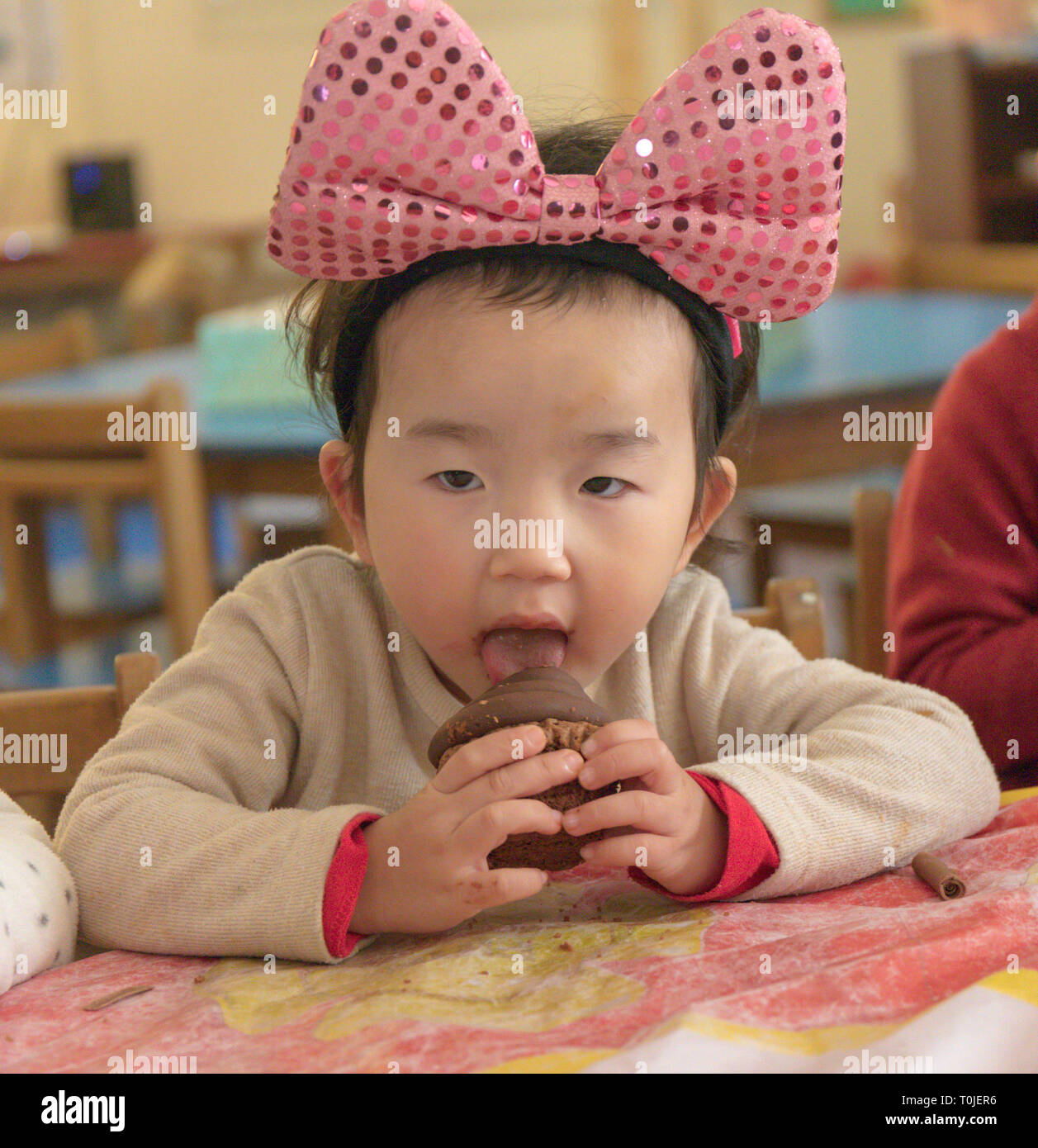 girl eating cupcake at preschool birthday party Stock Photo