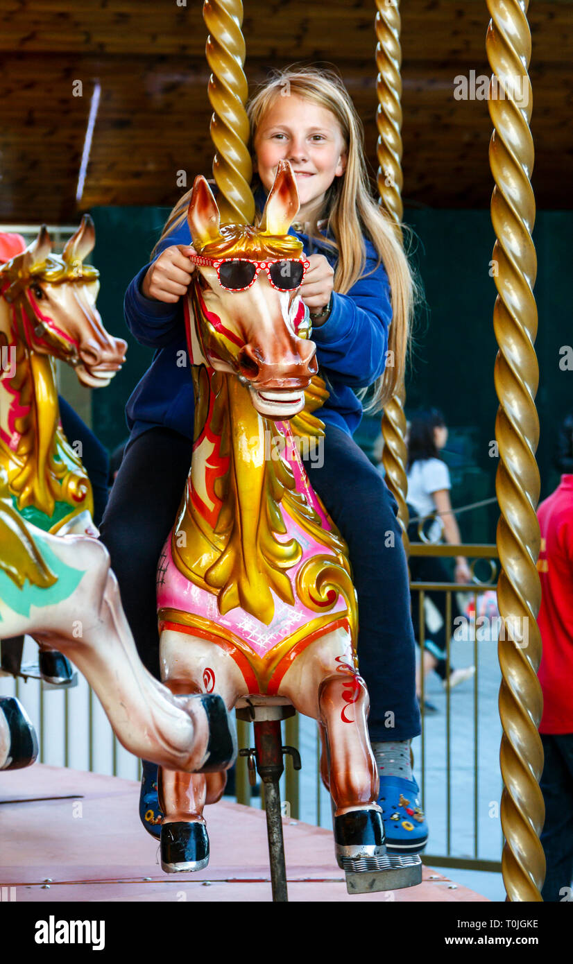 A young girl riding a horse on a traditional fairground carousel