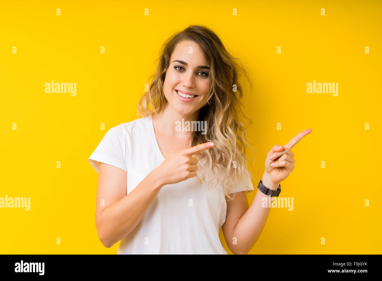 Young beautiful blonde woman over yellow background smiling and looking ...