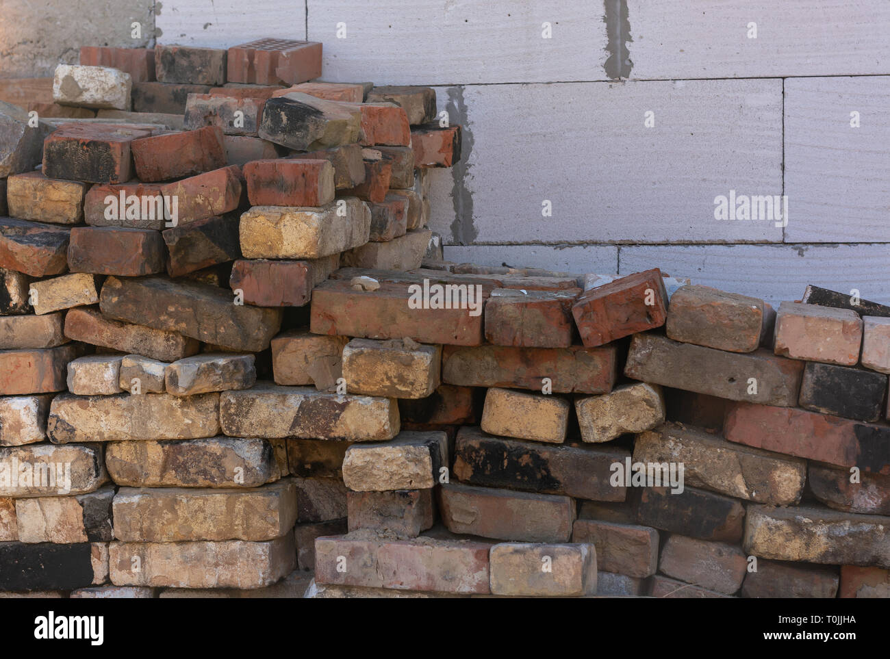 red bricks piled against a white wall Stock Photo