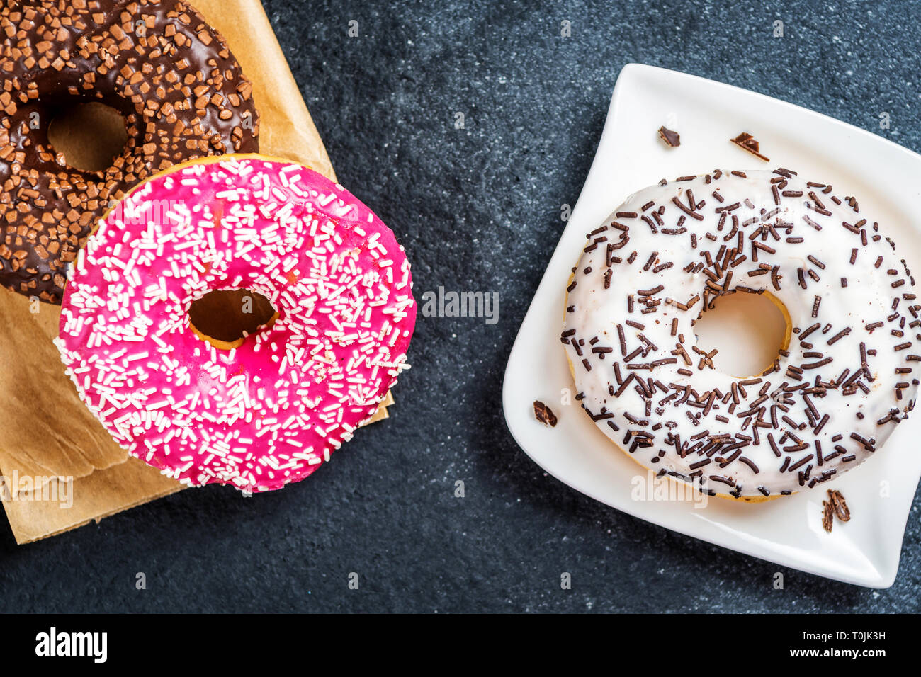 Chocolate, red, and white donuts on black stone table Stock Photo