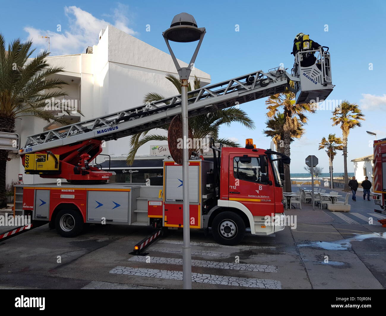 Can Picafort, Mallorca, Spain. 20th Mar, 2019. Firefighters put out fire on the roof of a building caused by a chimney, cutting the road. Credit: Sergiu Gabi Trasa/Alamy Live News Stock Photo