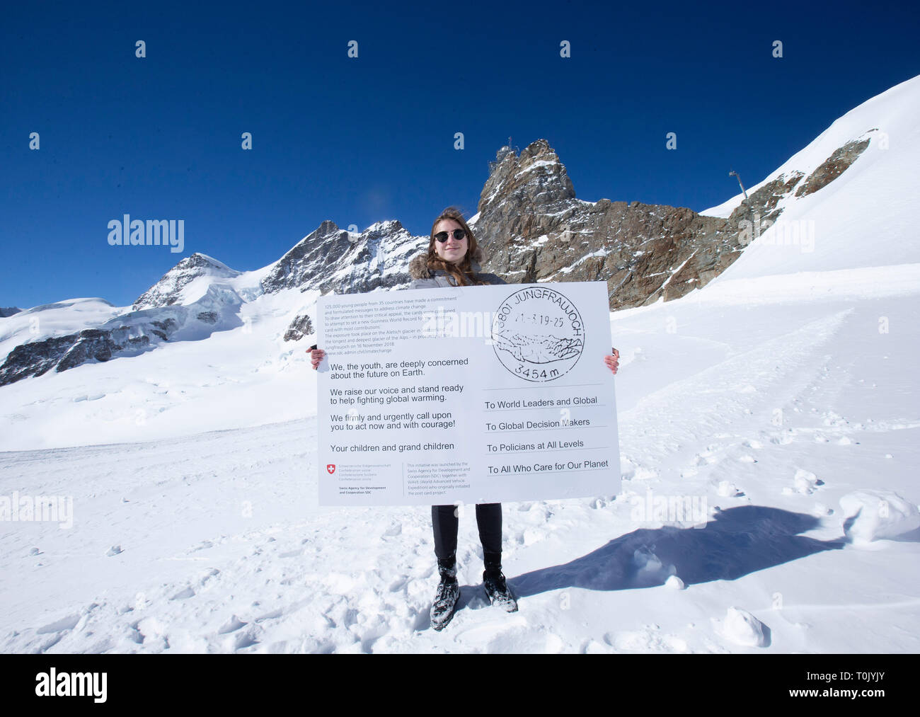 Jungfraujoch. 20th Mar, 2019. Swiss teenager Selma Schellenberg shows a copy of a postcard calling for action against climate change on the Aletsch glacier under Jungfraujoch in Switzerland, on March 20, 2019. Some 900 postcards from youths all over the world were stamped and sent on Wednesday from Europe's highest postbox on the Jungfraujoch peak, Switzerland, to global leaders, calling for action against climate change. Credit: Xu Jinquan/Xinhua/Alamy Live News Stock Photo