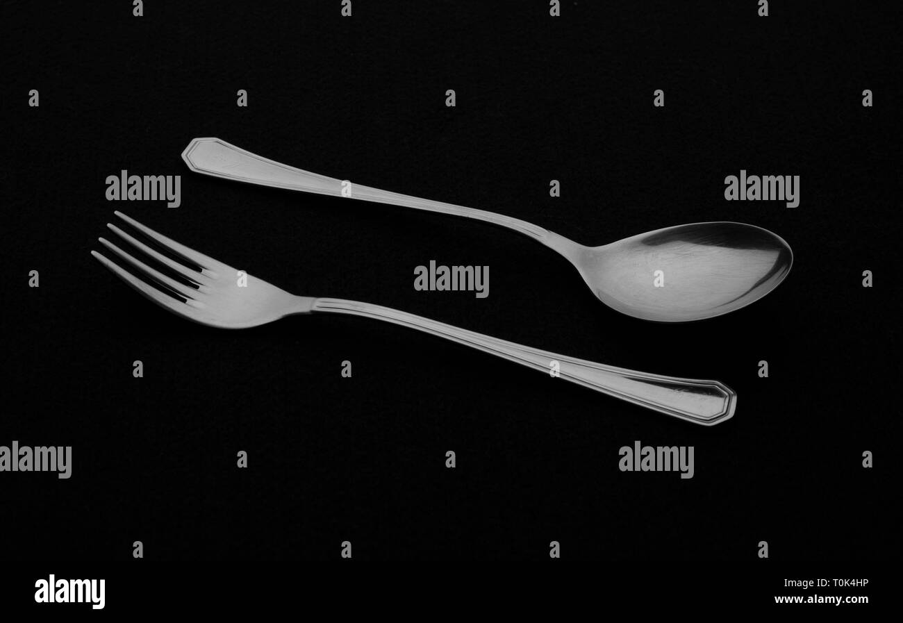 Metal cutlery on black background. Spoon and fork. Stock Photo