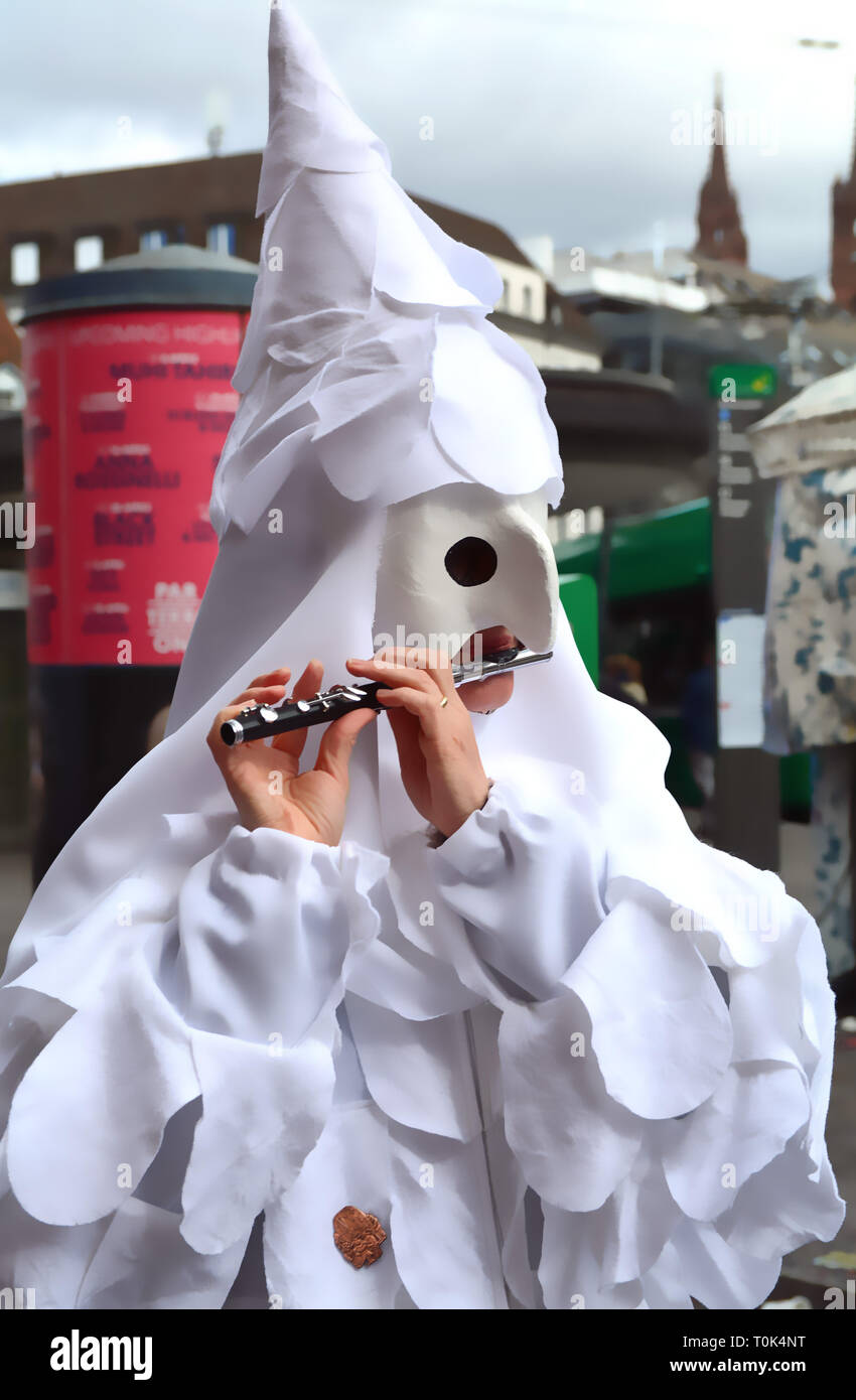 Closeup of a fife playing person wearing a white mask and white costume during the Basel carnival in Switzerland. Stock Photo