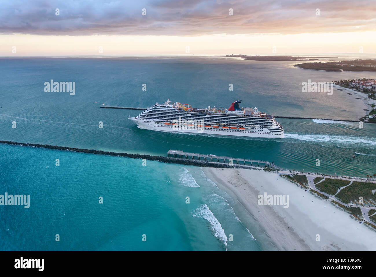 Cruise ship leaving Miami Port at dusk. Amazing aerial view from helicopter on a cloudy sunset. Stock Photo