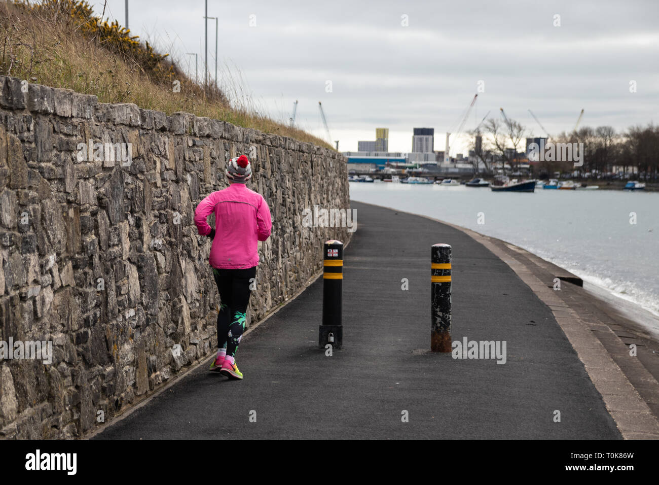 Woman in pink jogging on a footpath Stock Photo