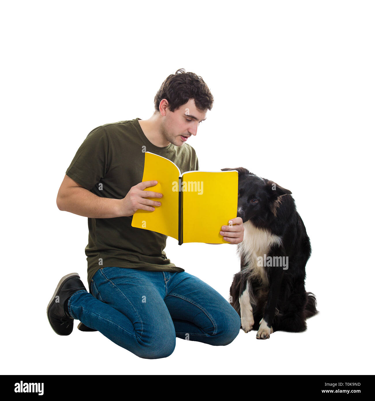 Funny purebred border collie dog and his master reading together an interesting book. Owner down on knees training his cute puppy isolated over white  Stock Photo
