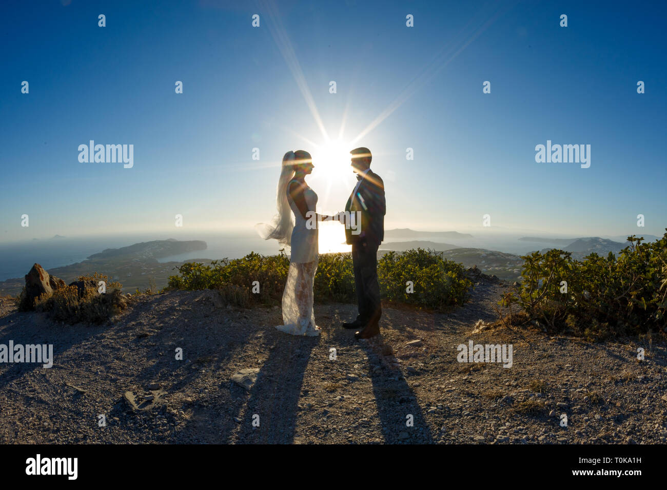 Silhouette of bride and groom on a high rock on a background of sea ...