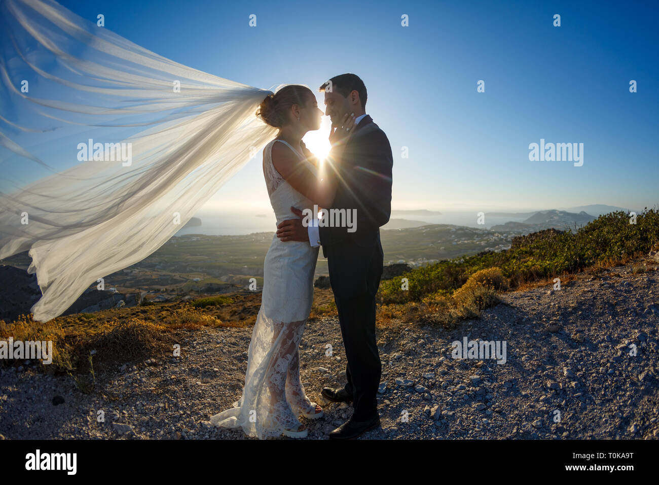 Silhouette of bride and groom on a high rock on a background of sea ...