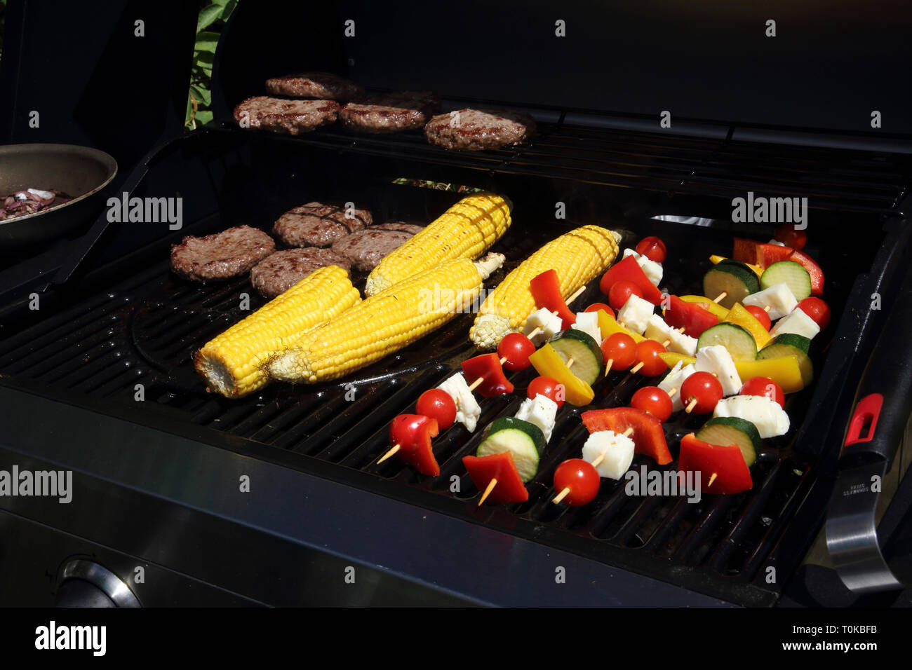 Cooking Kebabs, Corn on the Cob and Burgers on Barbeque in Garden Gillingham Dorset England Stock Photo