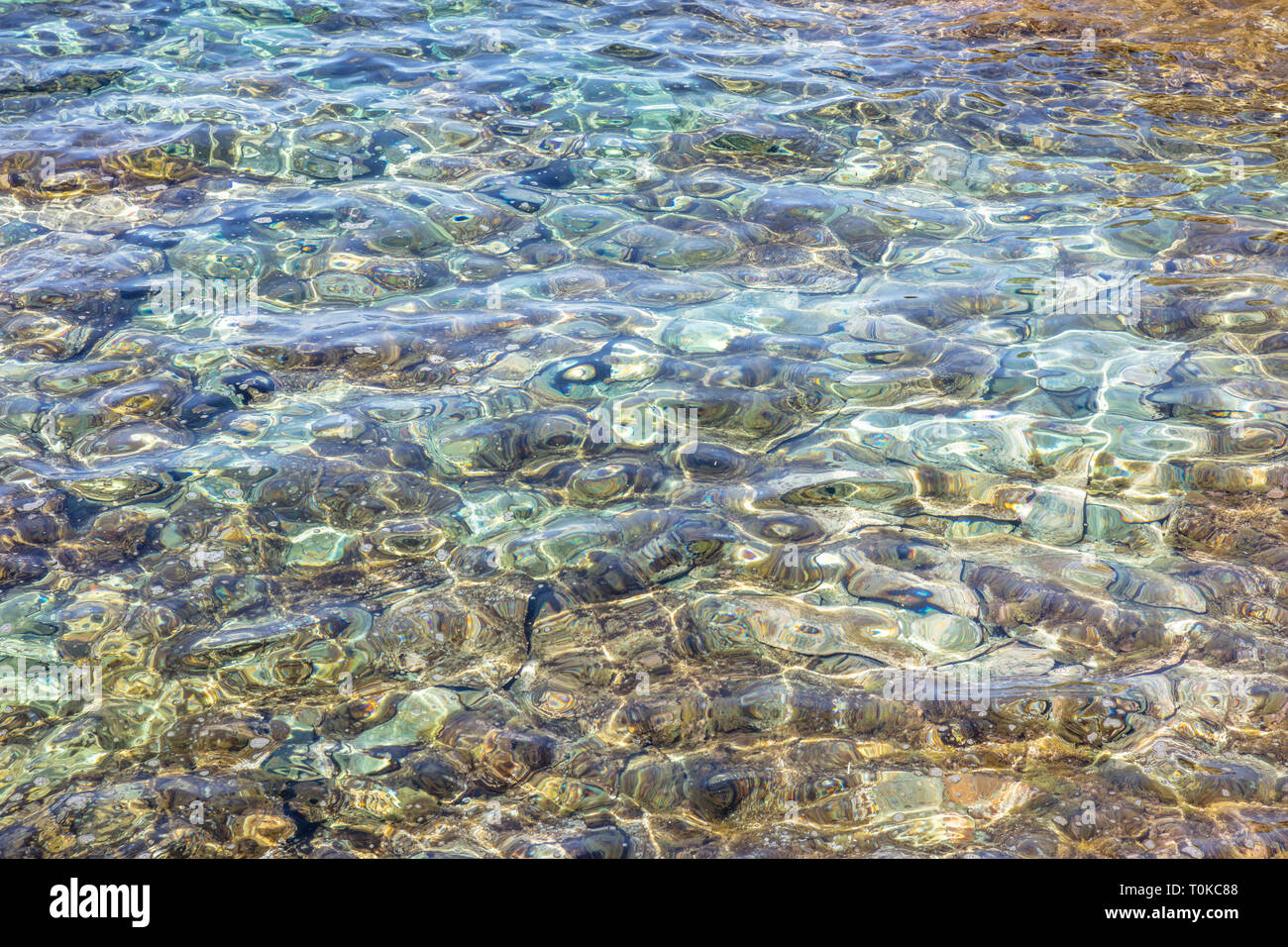 Clear crystal shallow blue sea water and rocky seabed background, high angle view Stock Photo