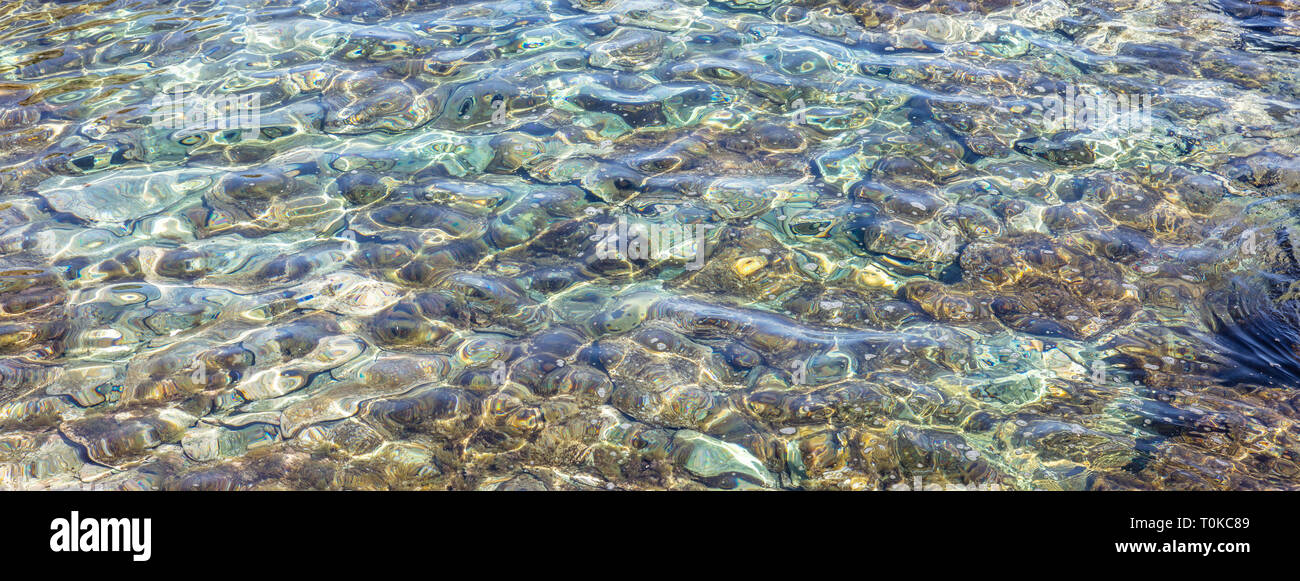 Clear crystal shallow blue sea water and rocky seabed background, banner Stock Photo