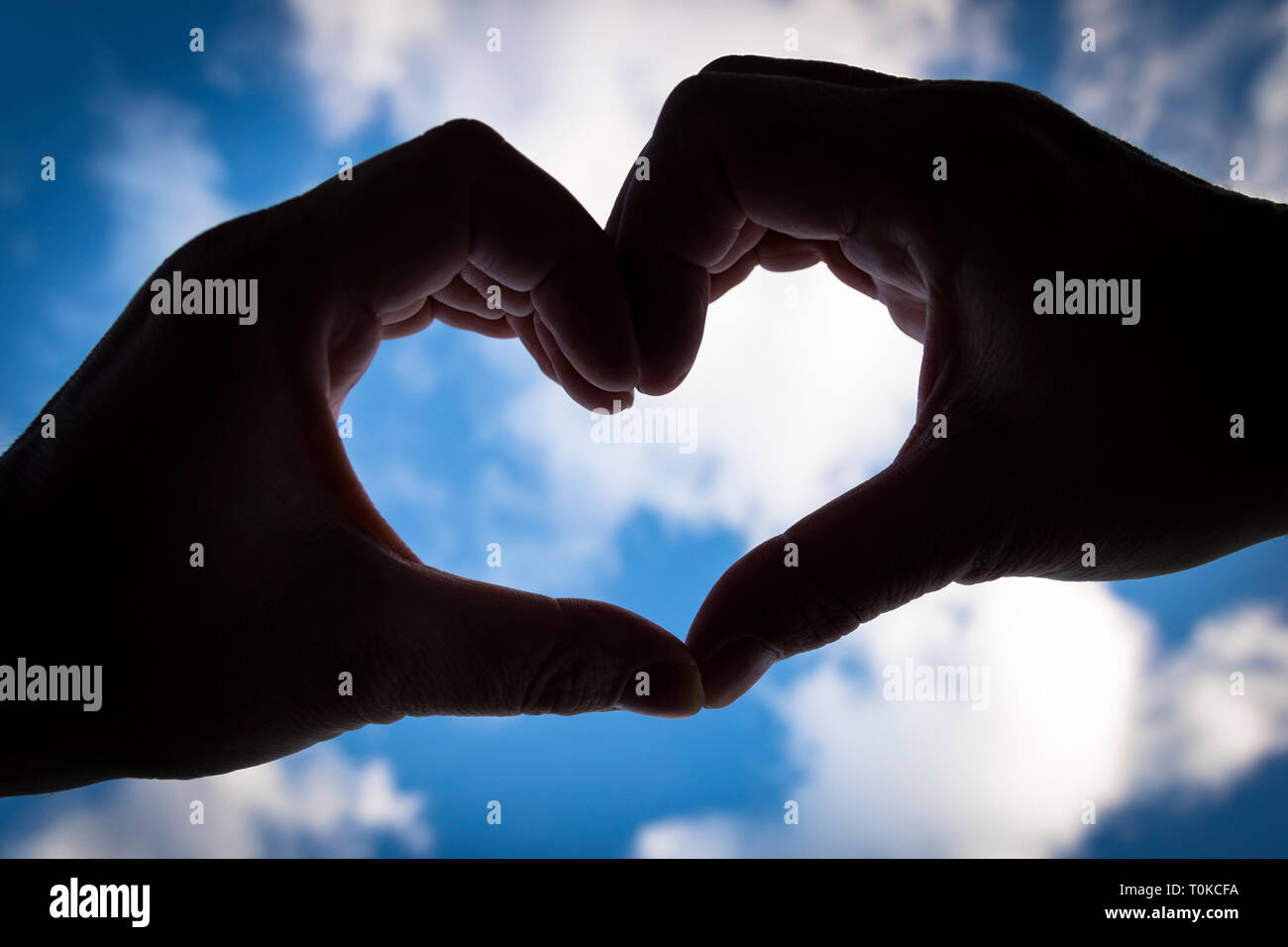 Silhouette of hands making a heart against a bright calm blue sky Stock ...