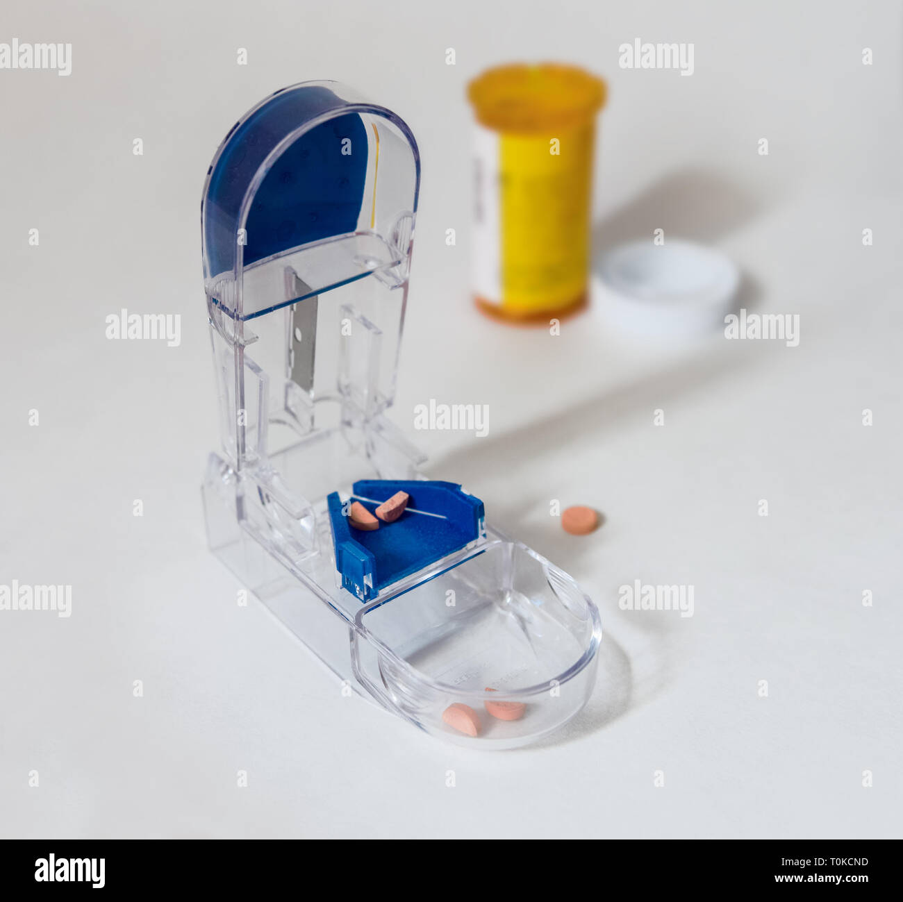 On a white surface we see a pill splitter, halved doses and a