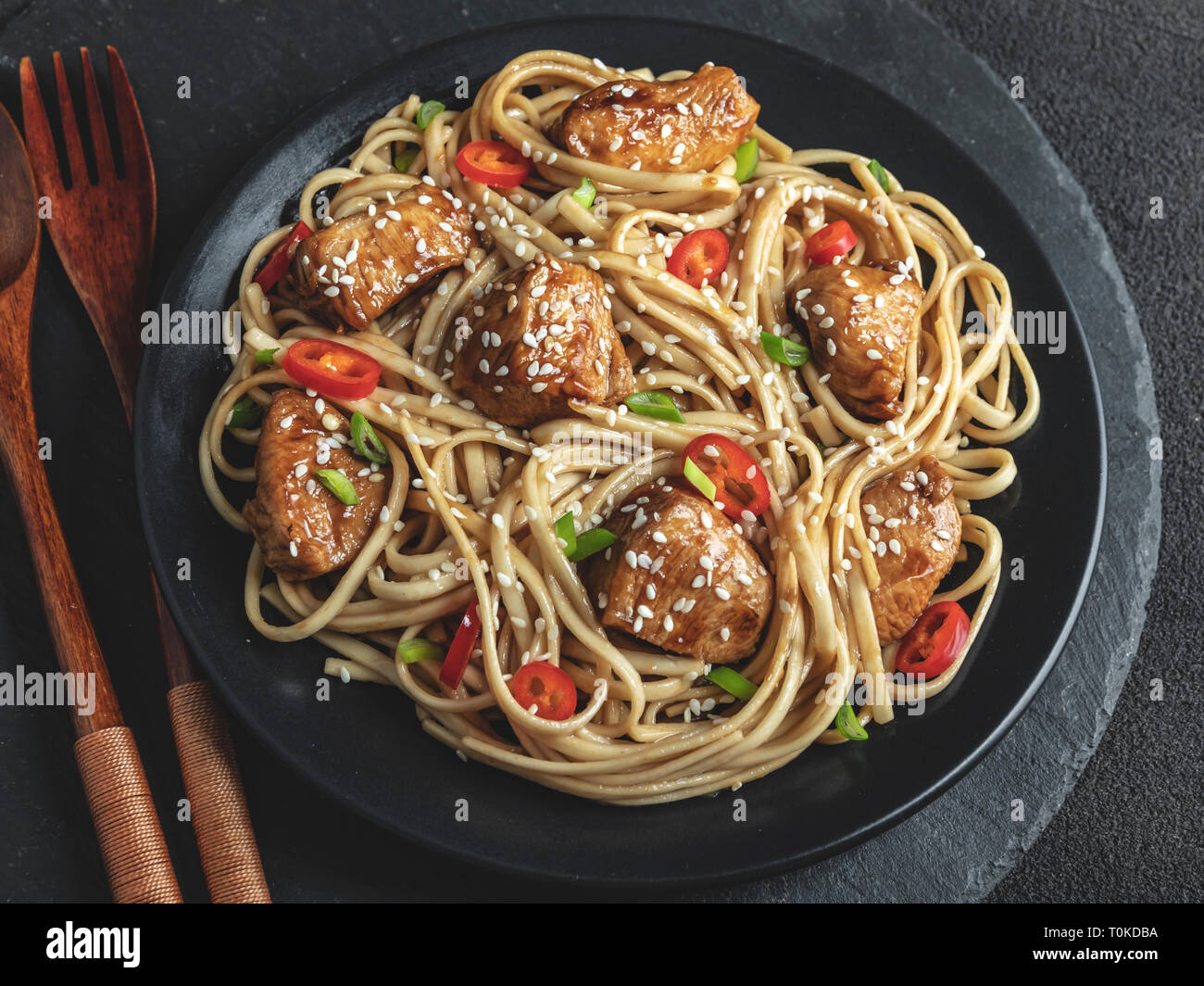 Asian noodles with chicken teriyaki , sesame, rustic stone background. Closeup. Chinese/Japanese
