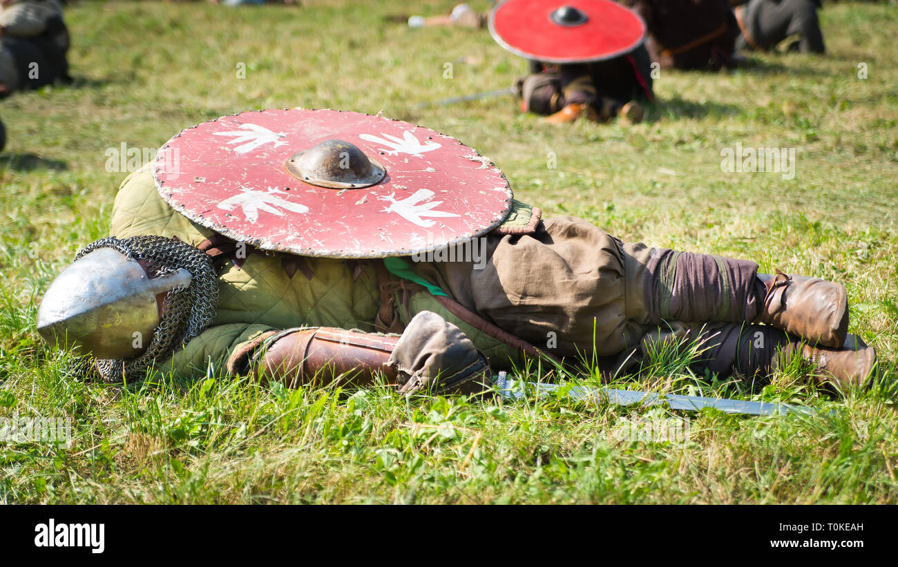 Defeated warrior lying on the grass with his shield Stock Photo