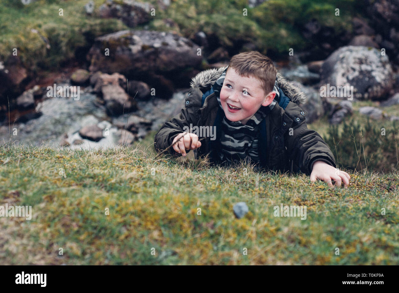 Small 7,8,9 year old boy smiling and climbing outdoors Stock Photo